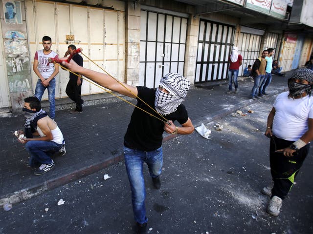 Palestinian protesters throw stones during clashes in the West Bank city of Hebron
