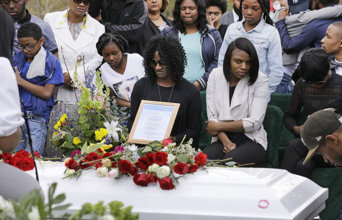 Gloria Darden, mother of Freddie Gray, center, sits in front of his casket at his burial,