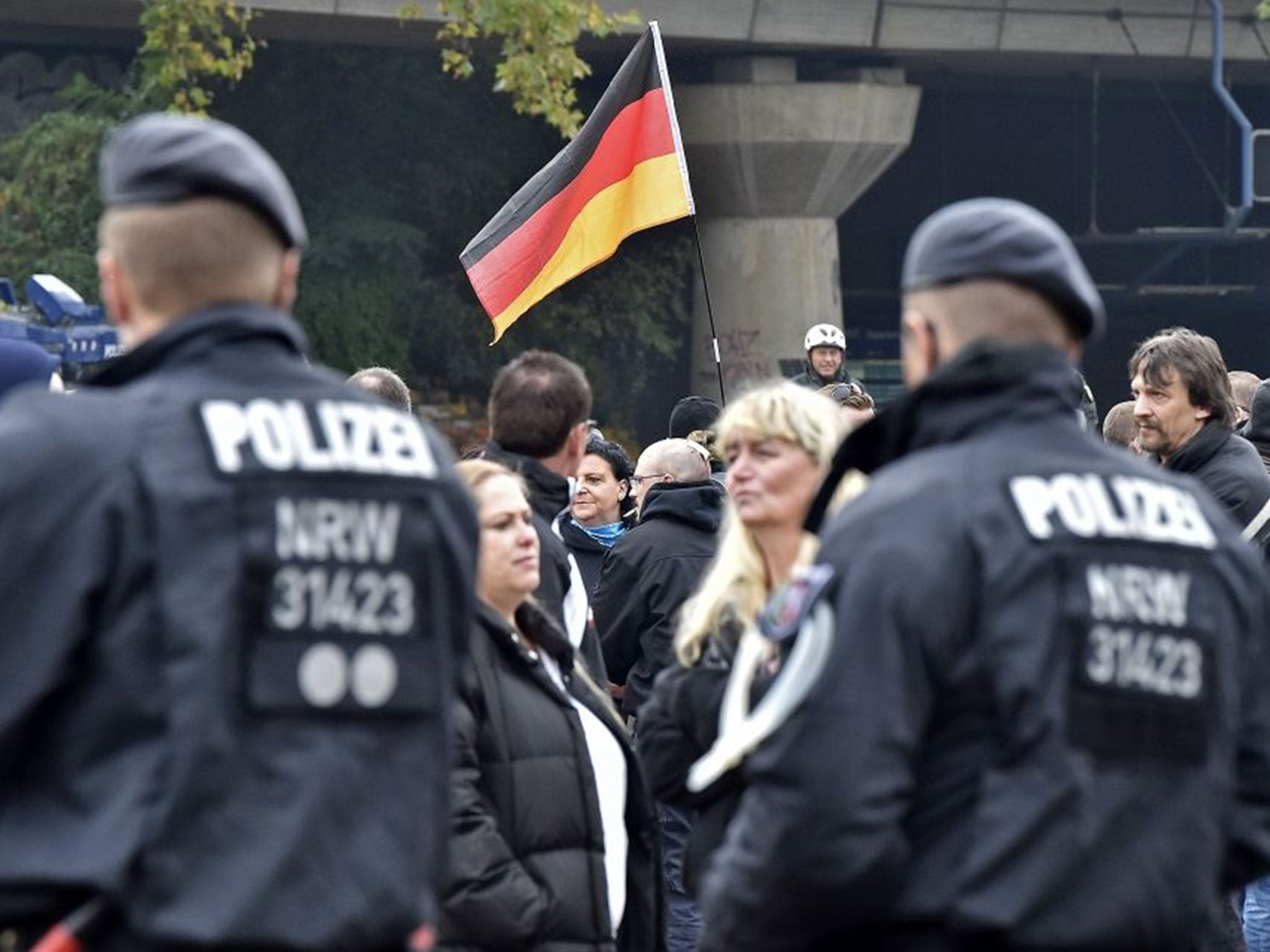 Far-right protestors hold a German flag as police secure streets in Cologne, Germany