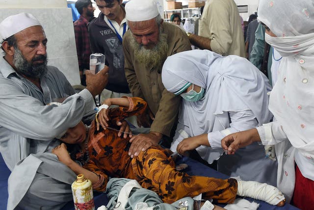 Pakistani paramedics treat a girl injured in an earthquake at a hospital in Peshawar