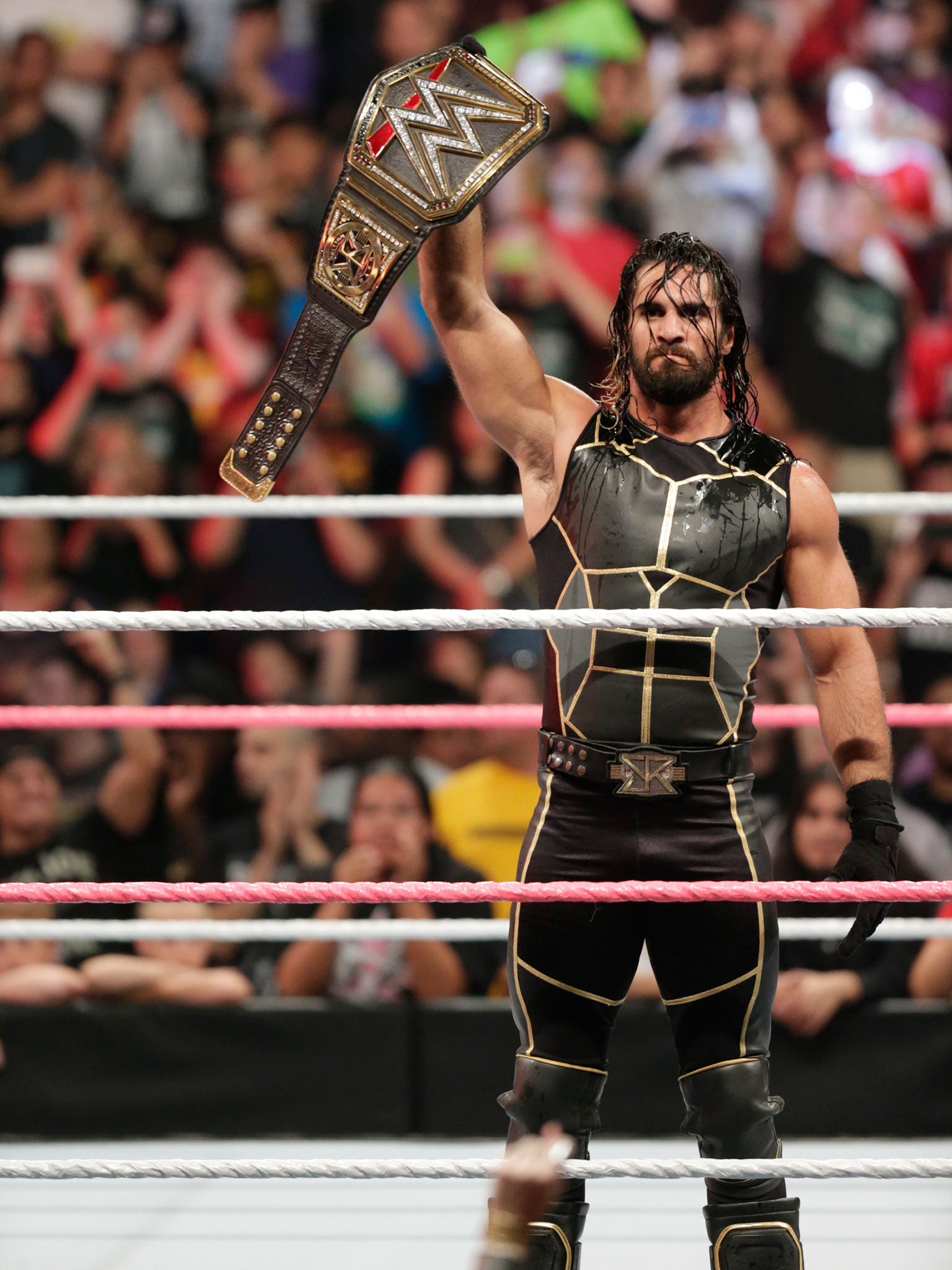 Seth Rollins holds up his WWE World Heavyweight title