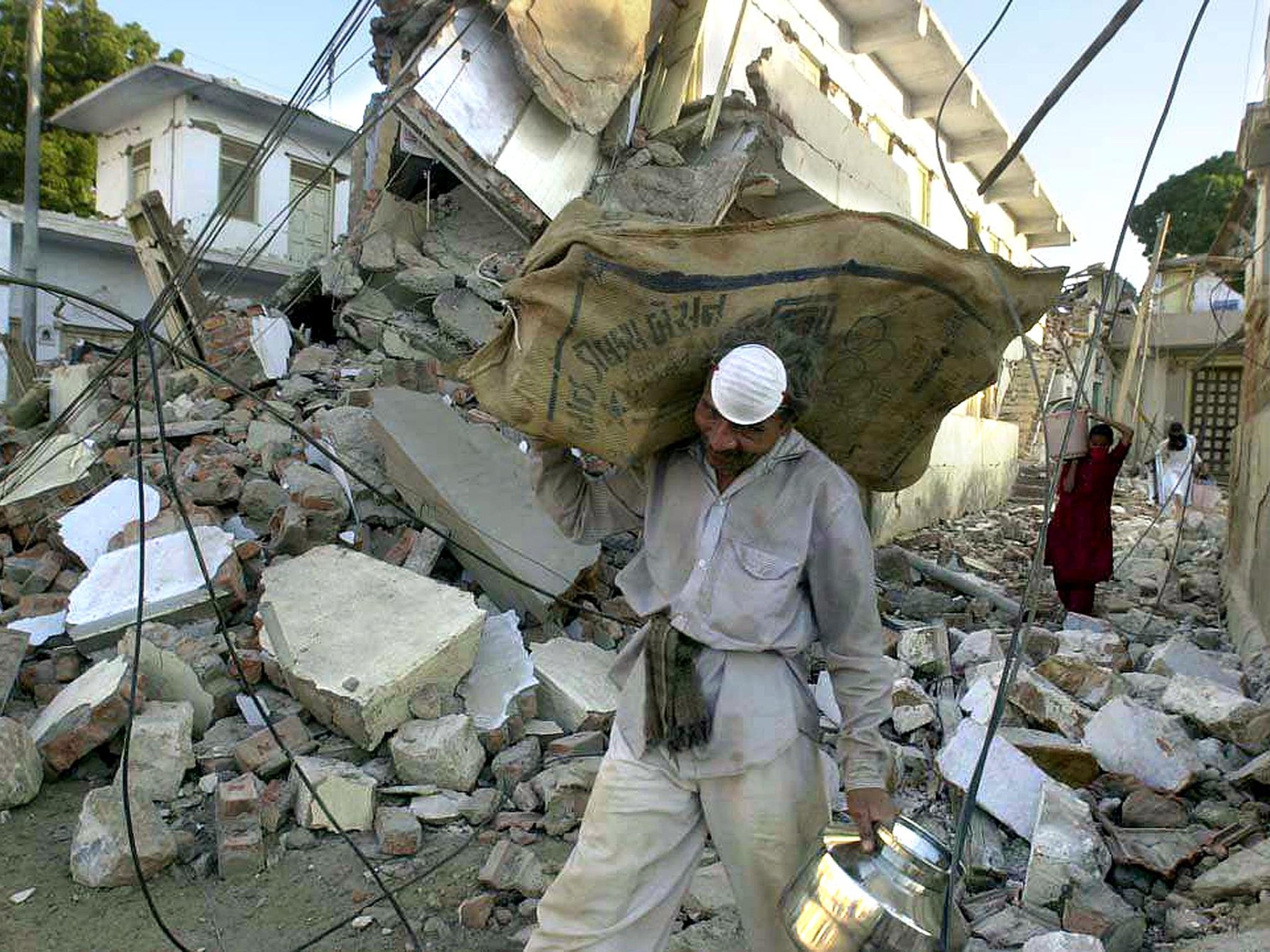 A worker carries the belongings of a resident, retrieved from the earthquake rubble earlier, through the streets of Bhachau, January 2001