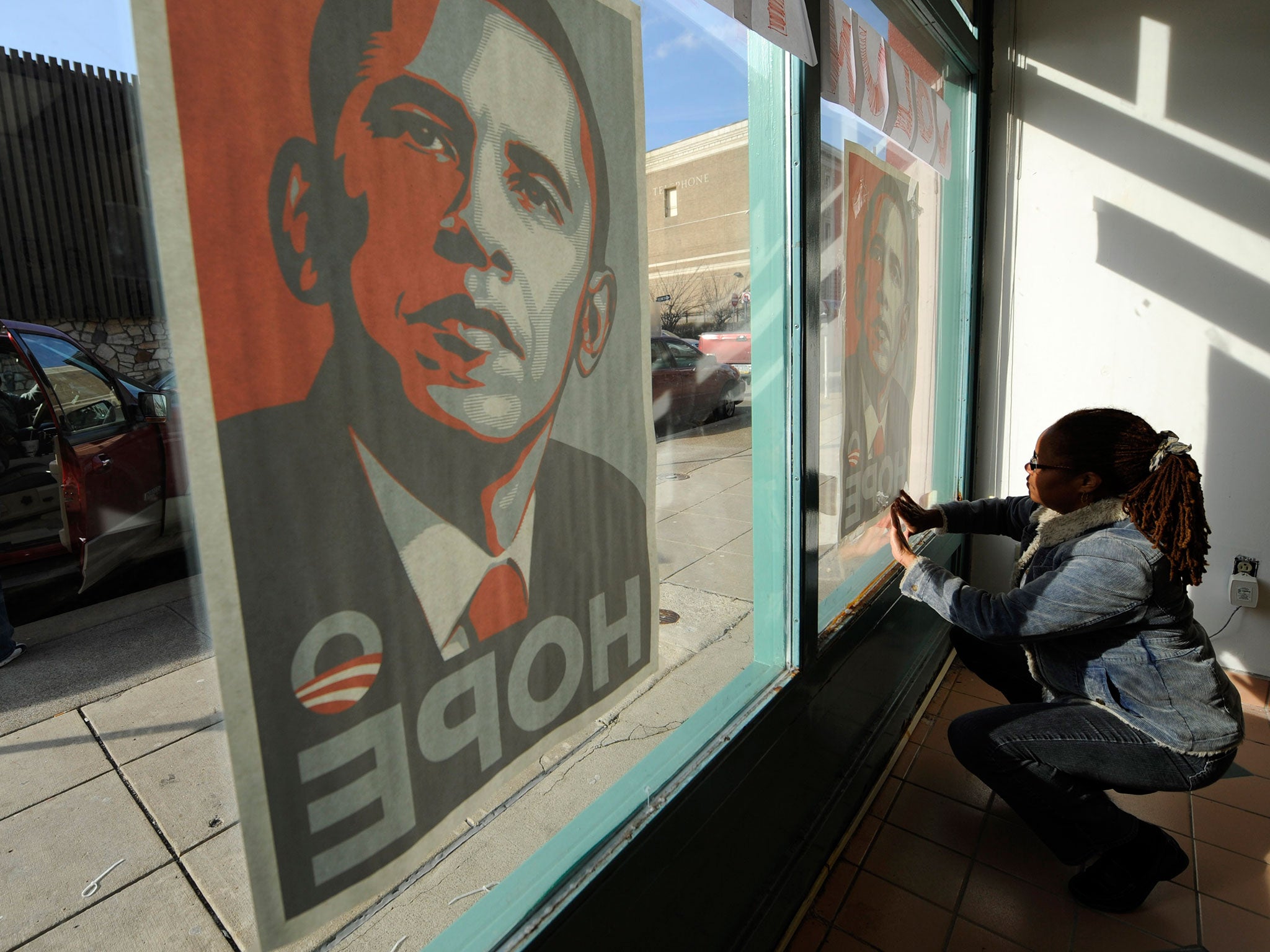 A volunteer for Barack Obama's 2008 presidential election campaign tapes up posters in Pittsburgh, Pennsylvania