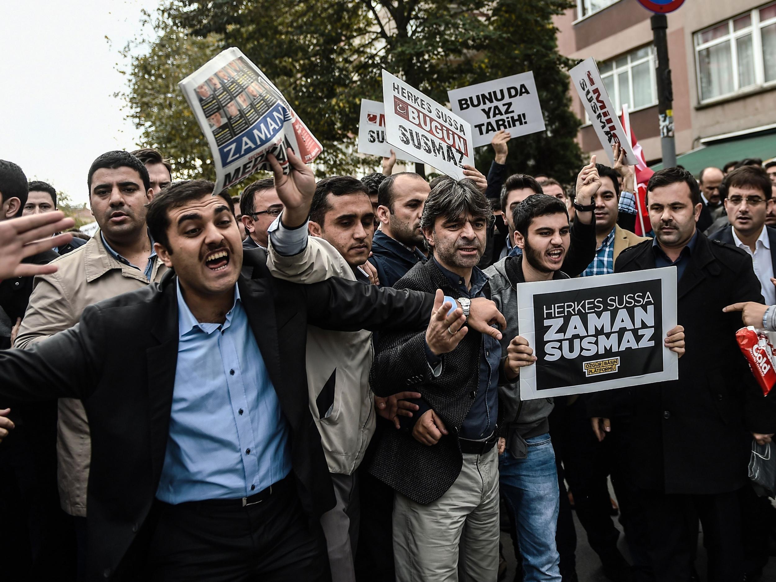 Supporters of Bugun and Kanalturk media groups shout slogans towards Turkish riot police and hold placards reading ' Bugun is not alone-if everybody is silent , Bugun won't be '