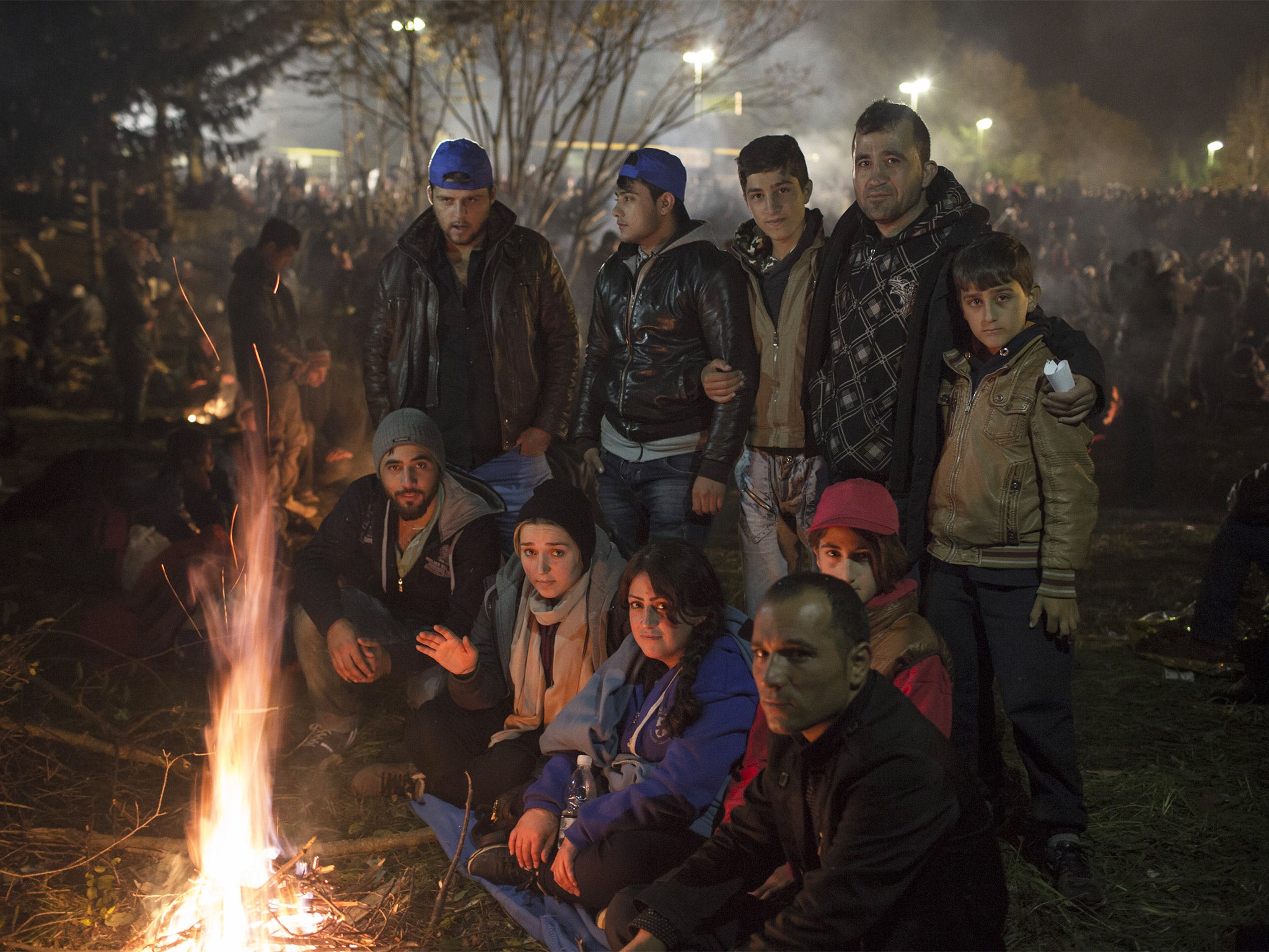 Kawphar Zangana, back right holding his sons, is surrounded by friends and family trying to stay warm while waiting in no-man’s-land on the Slovenian border
