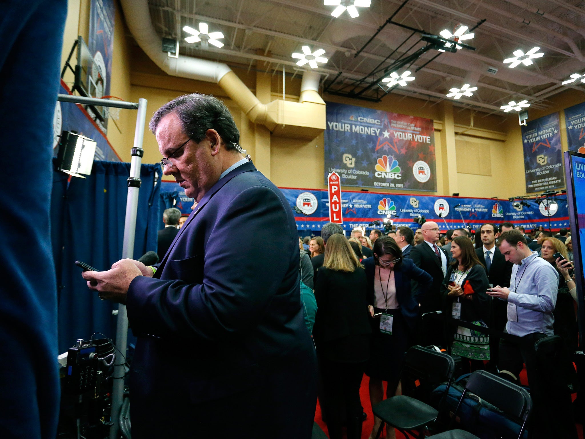 Chris Christiechecks his phone in the spin room following the debate