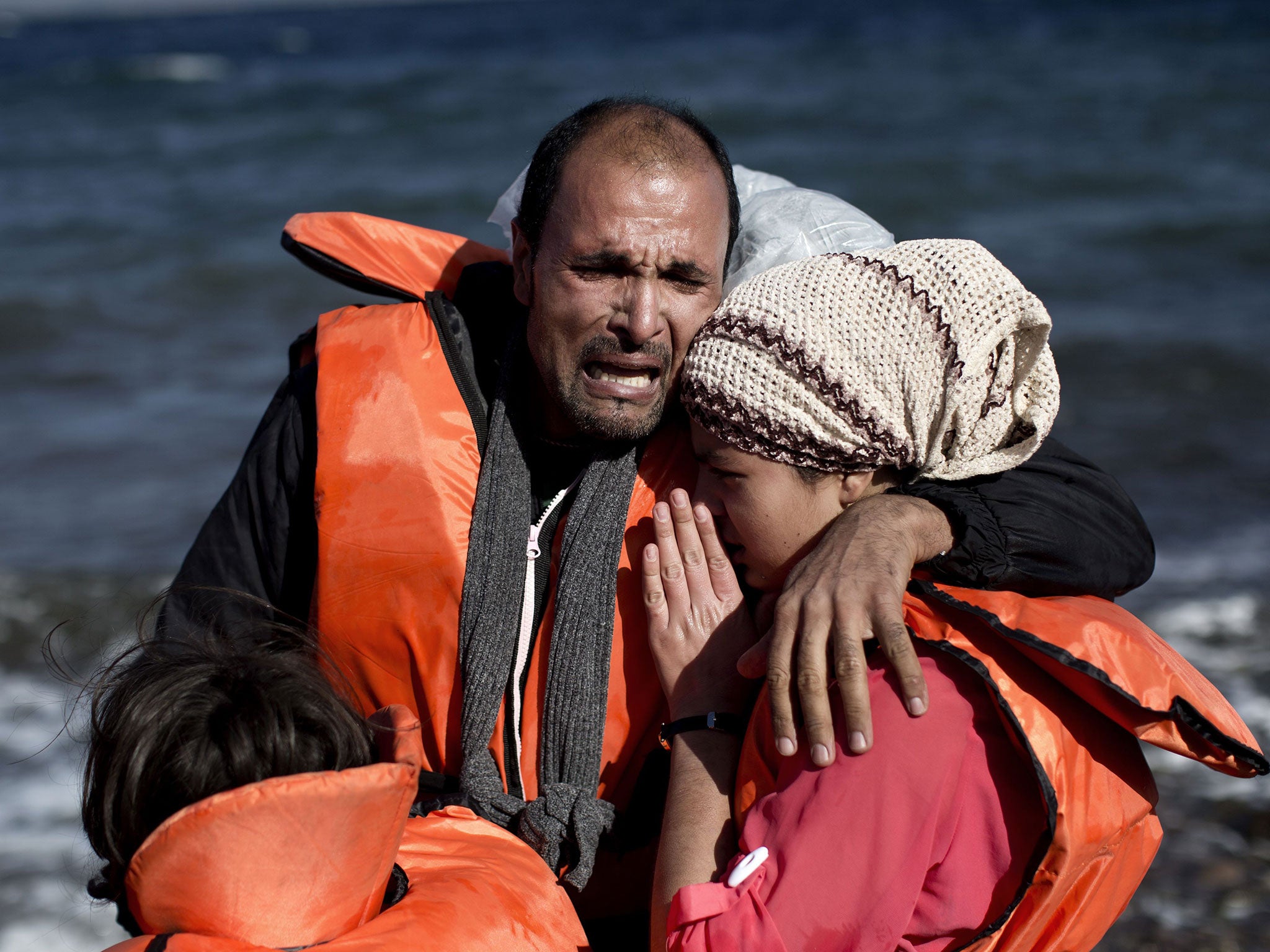 A family reacts after arriving, with other refugees and migrants, on the Greek island of Lesbos, on October 28, 2015,