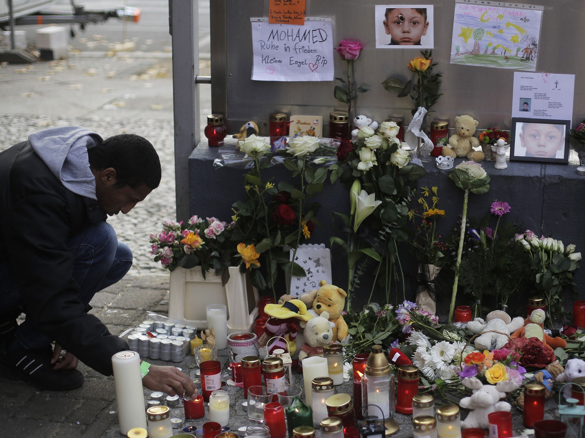 A man lights a candle at a memorial site for the killed 4-year-old Bosnian migrant boy Mohamed Januzi at the State Office of Health and Welfare (Lageso) in Berlin, Germany, on 30 October