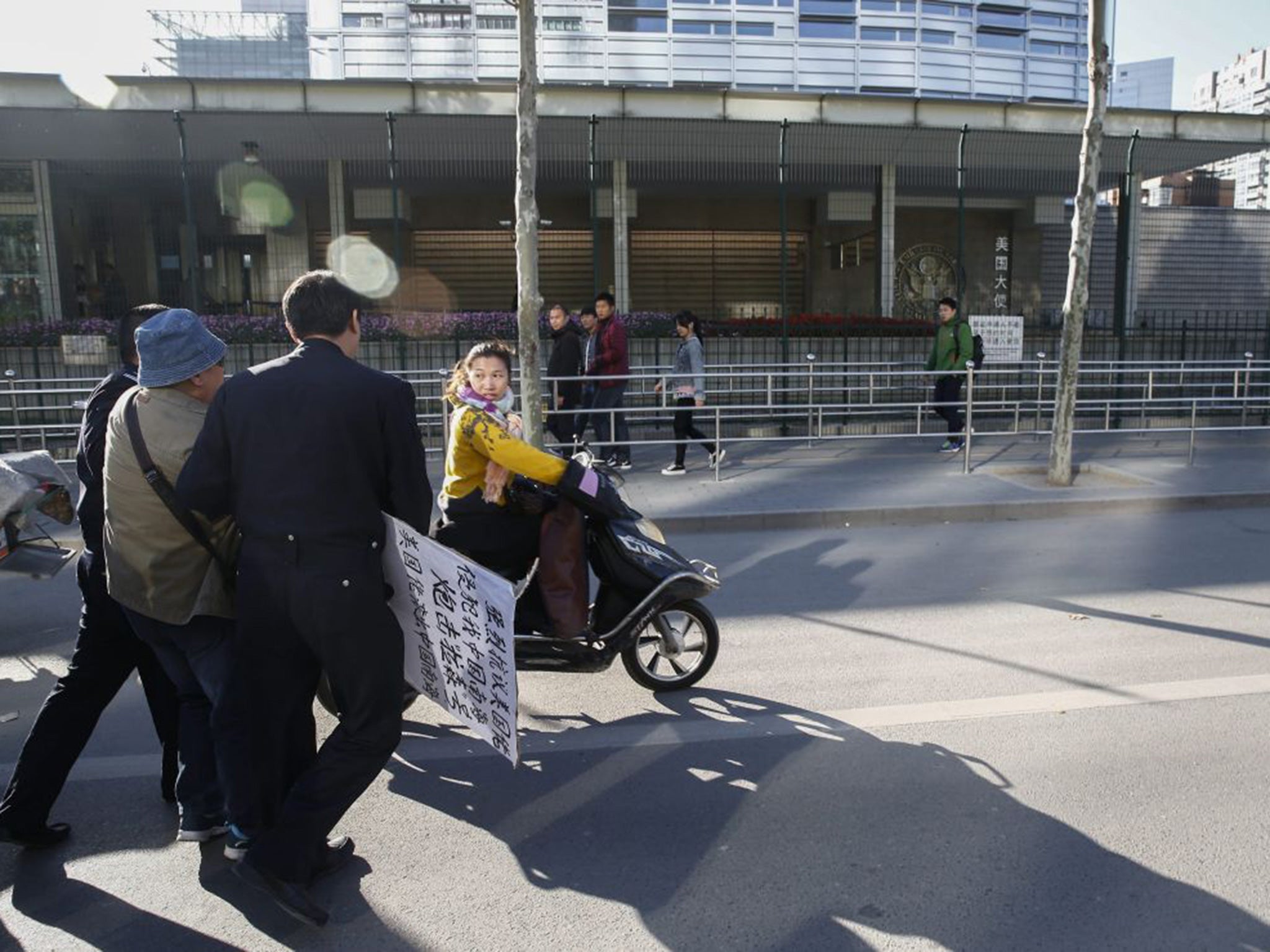 A protester (Left, inhat) holding a sign that reads 'Strongly protest against US encroachment on South China Sea is taken away by two Chinese police after trying to protest against the United States outside the US Embassy in Beijing