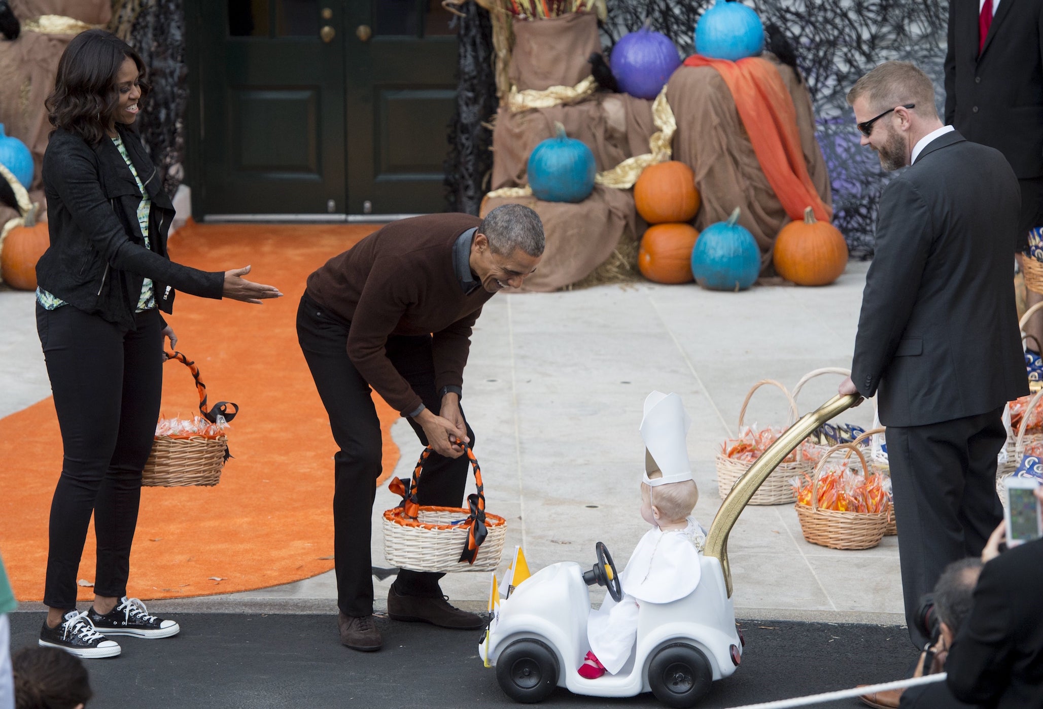 US President Barack Obama and First Lady Michelle Obama greet a young child dressed as the Pope and riding in a 'Popemobile' as he hands out treats to children trick-or-treating for Halloween on the South Lawn of the White House in Washington, DC, October 30, 2015