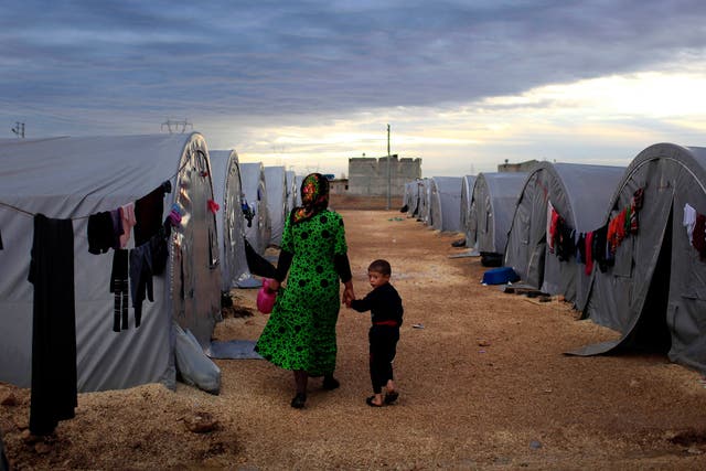 A Kurdish refugee mother and son from the Syrian town of Kobani walk beside their tent in a camp in the southeastern town of Suruc on the Turkish-Syrian border