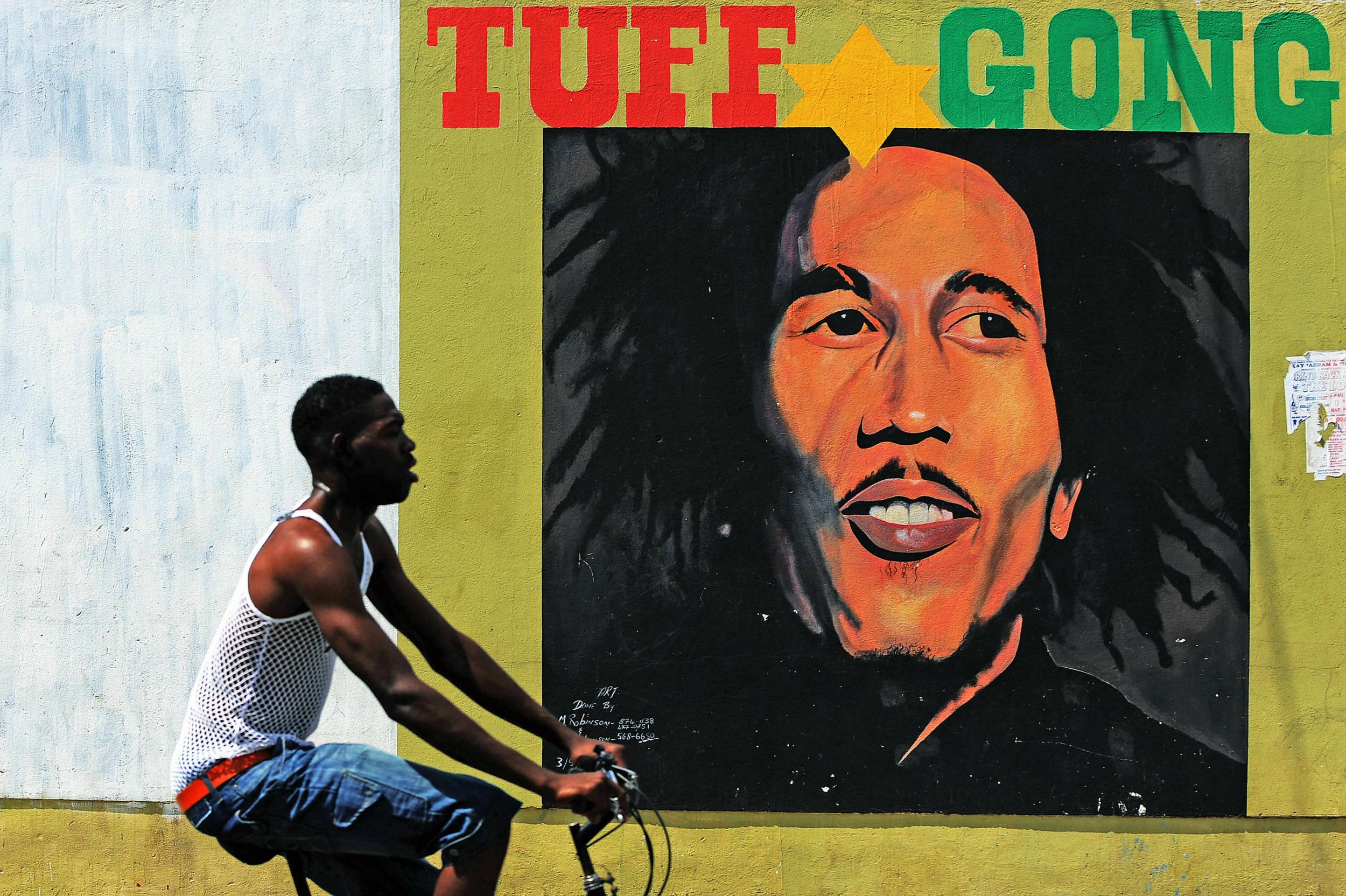 Man cycles past image of Bob Marley in Kingston, Jamaica