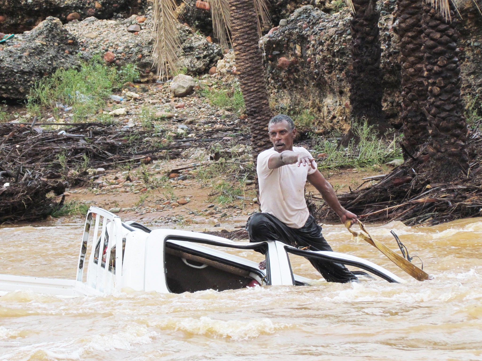 A man tries to save his vehicle as it is swept away by flood waters in Yemen’s island of Socotra