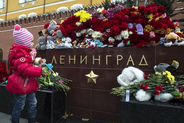 A young mourner places toys at the Tomb of the Unknown Soldier in Moscow for the crash victims