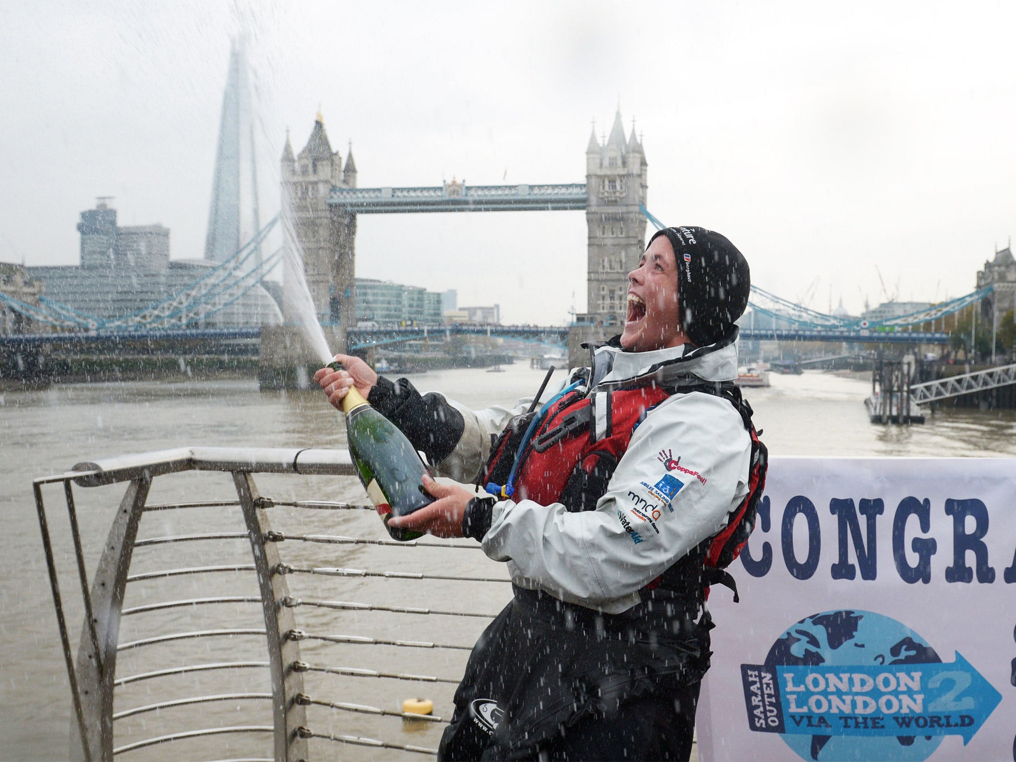 British adventurer Sarah Outen sprays champagne to celebrate after kayaking under Tower Bridge to complete her challenge