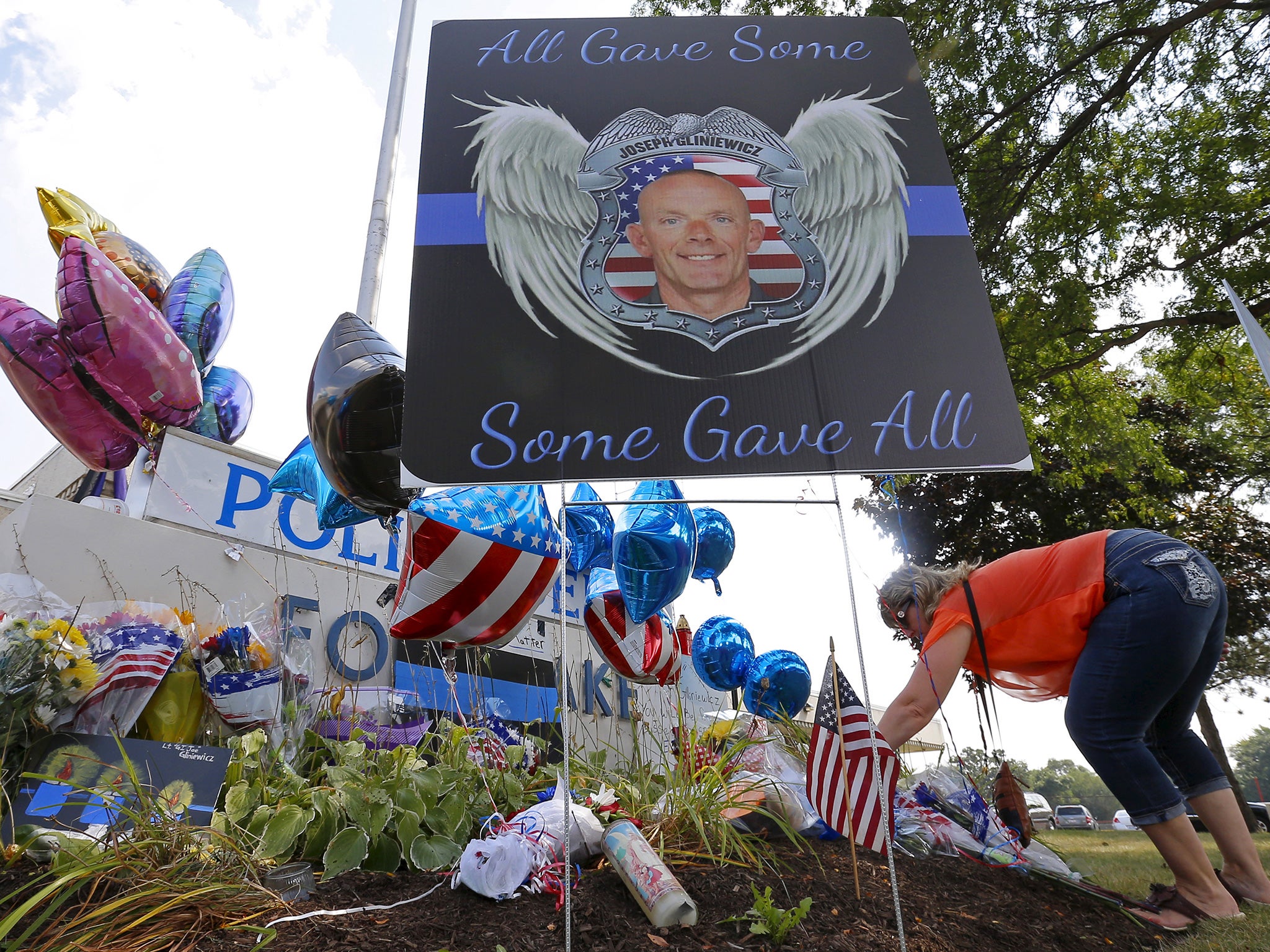 A woman lays flowers at a vigil for slain Fox Lake Police Lieutenant Charles Joseph Gliniewicz