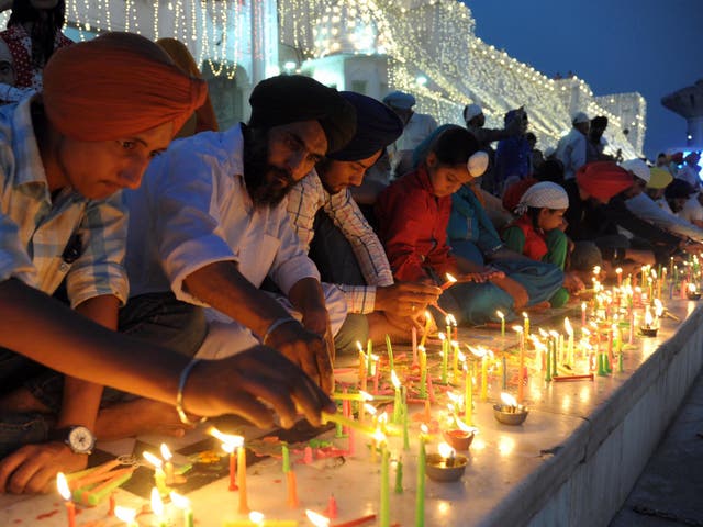 Indian Sikh devotees light candles on the occasion of Bandi Chhor Divas, or Diwali, at the illuminated Golden Temple in Amritsar, India