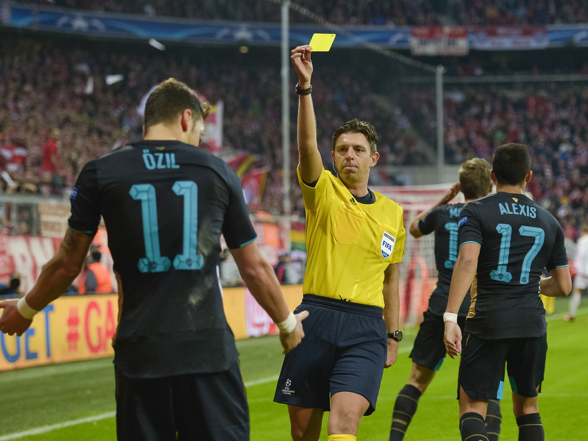 Mesut Ozil receives a yellow card for a hand-ball