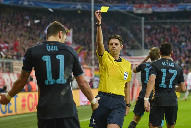 Mesut Ozil receives a yellow card for a hand-ball 