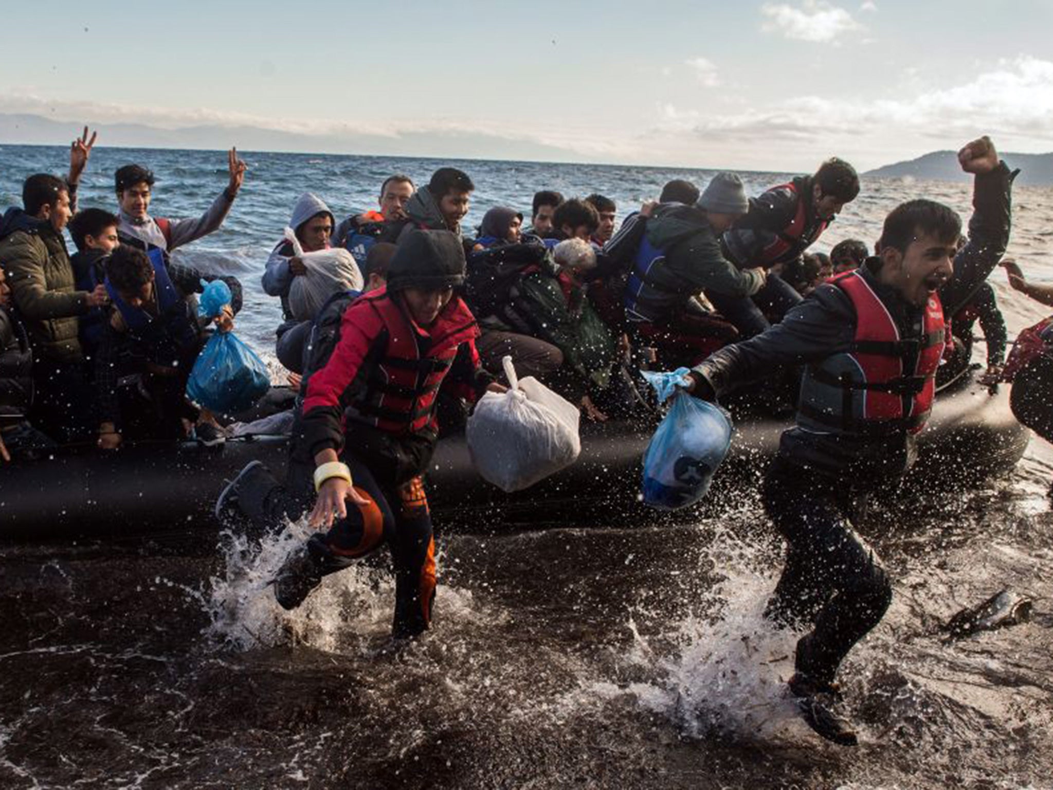 Refugees embark from a dinghy on the shores on Lesbos