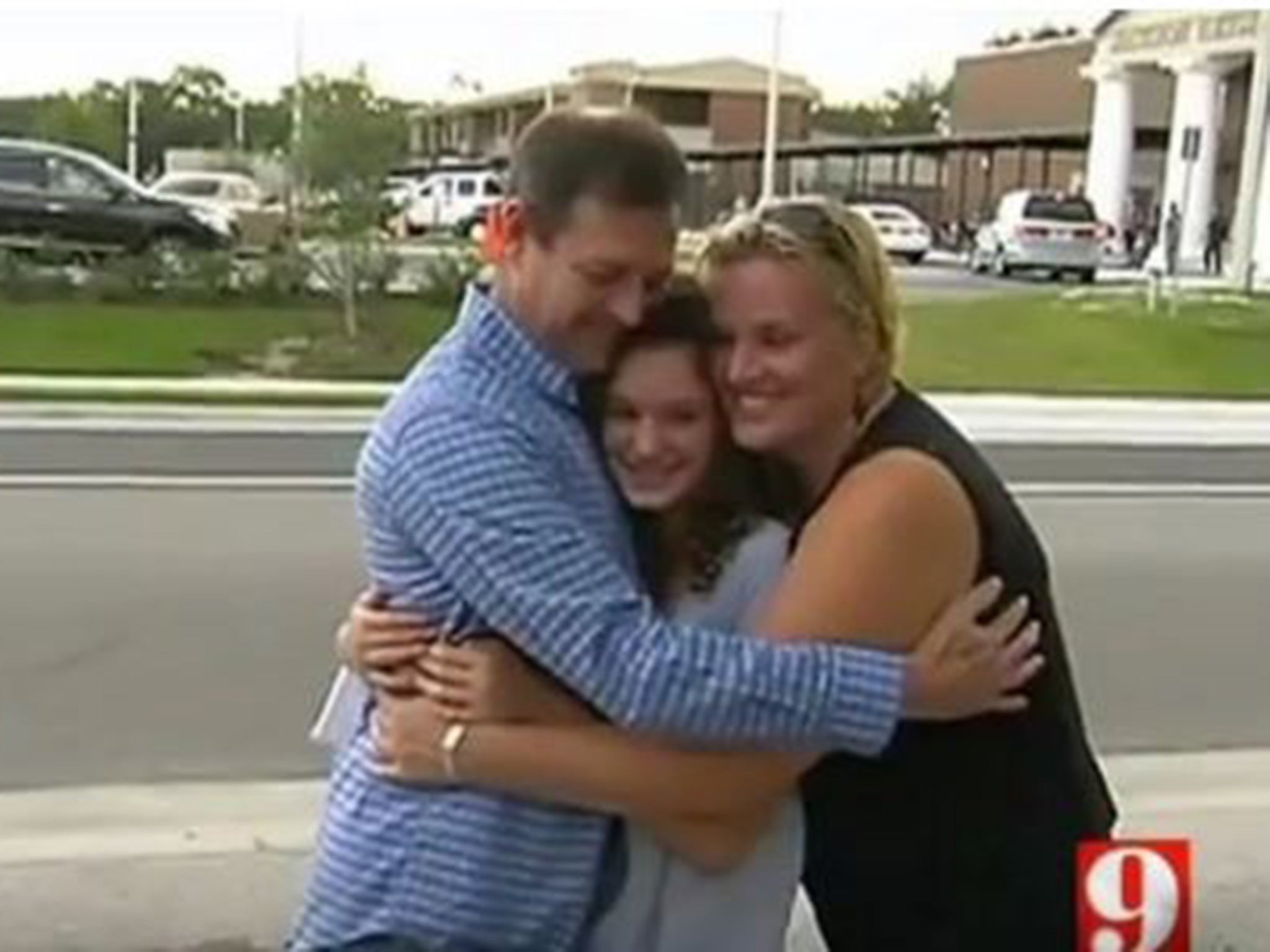 Ella Fishbough, 14, receives a hug from her parents