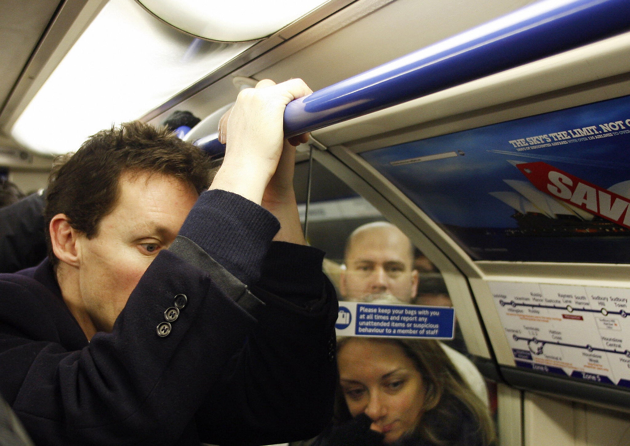 A man hangs onto a rail on the London Underground