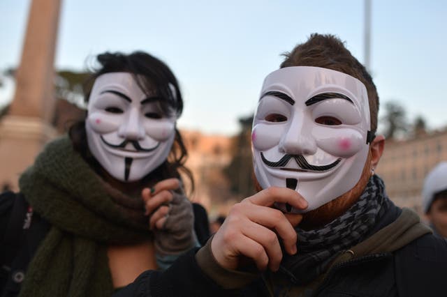 Protesters wear Guy Fawkes masks.