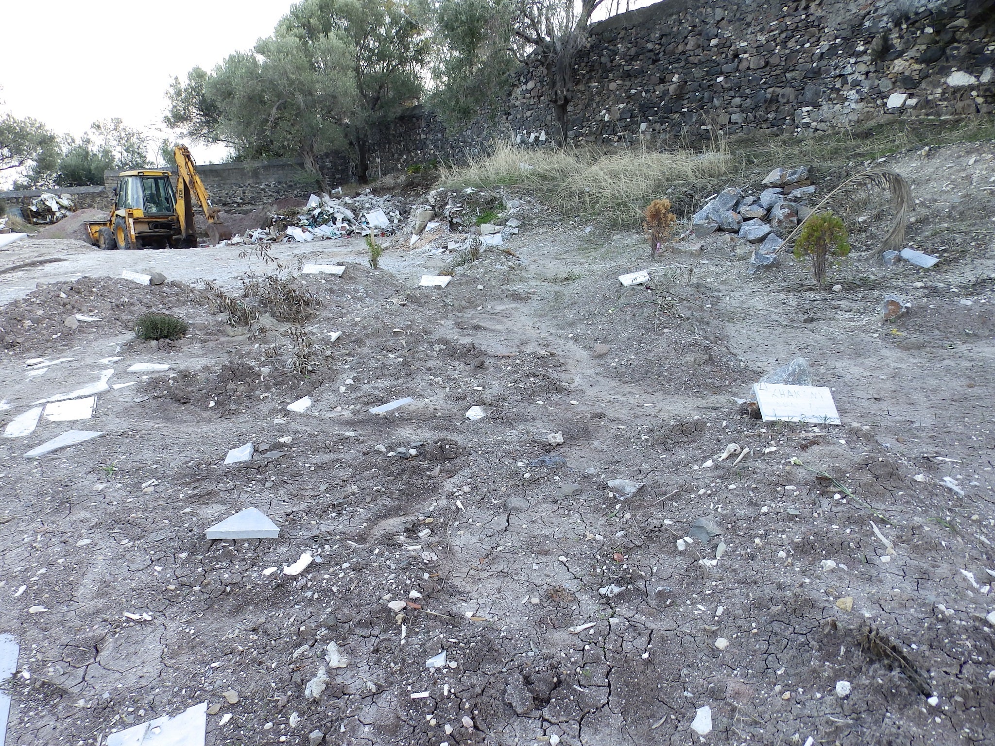 A wall is being knocked down to make more space for refugees' bodies at the Agios Panteleimonas cemetery in Mytilene, Lesbos.