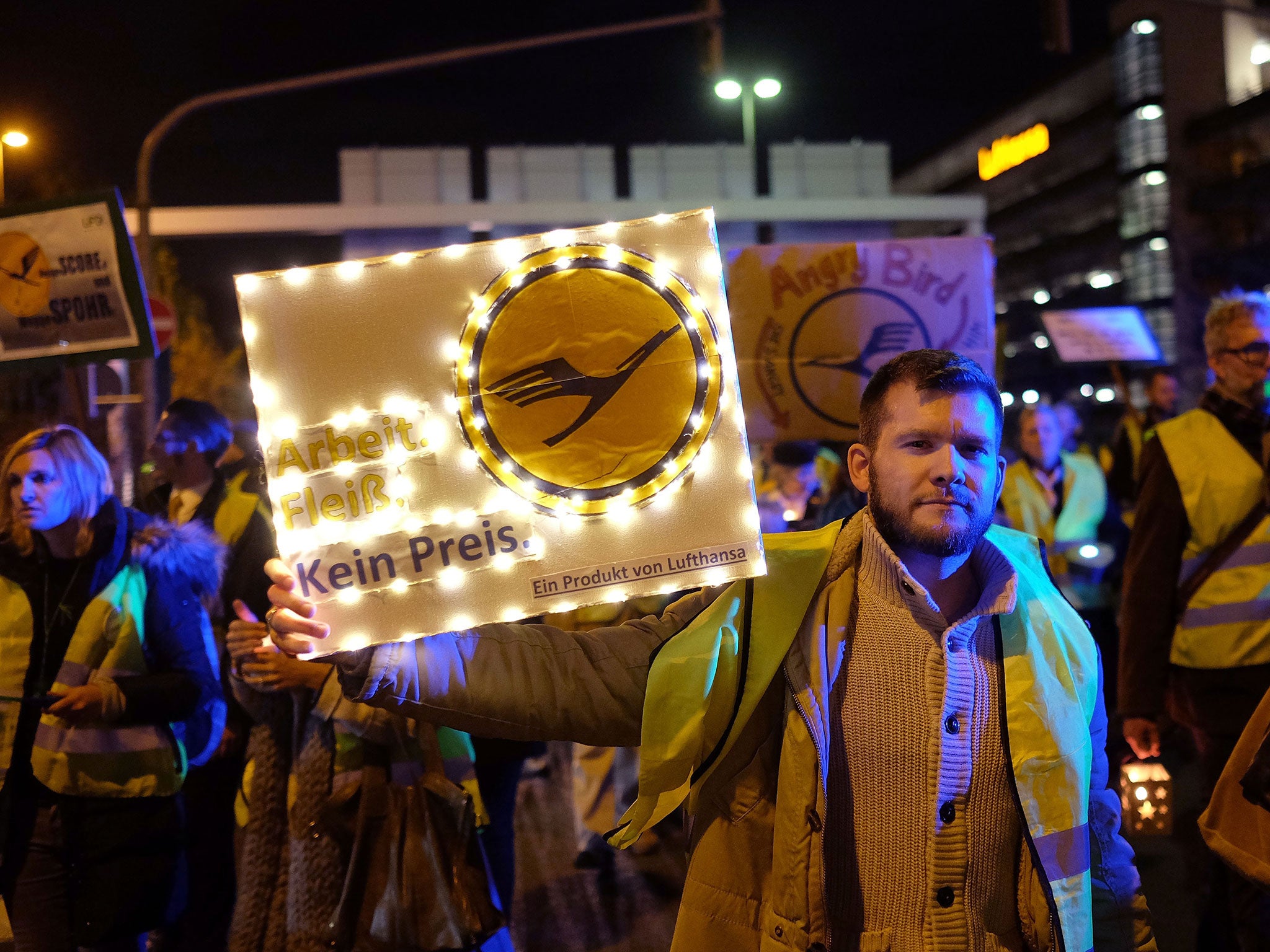 Lufthansa flight crew members walk with candles and banners to the 'Lufthansa Aviation Center' at Frankfurt Airport during an initial strike over salaries on November 6, 2015 in Frankfurt, Germany.