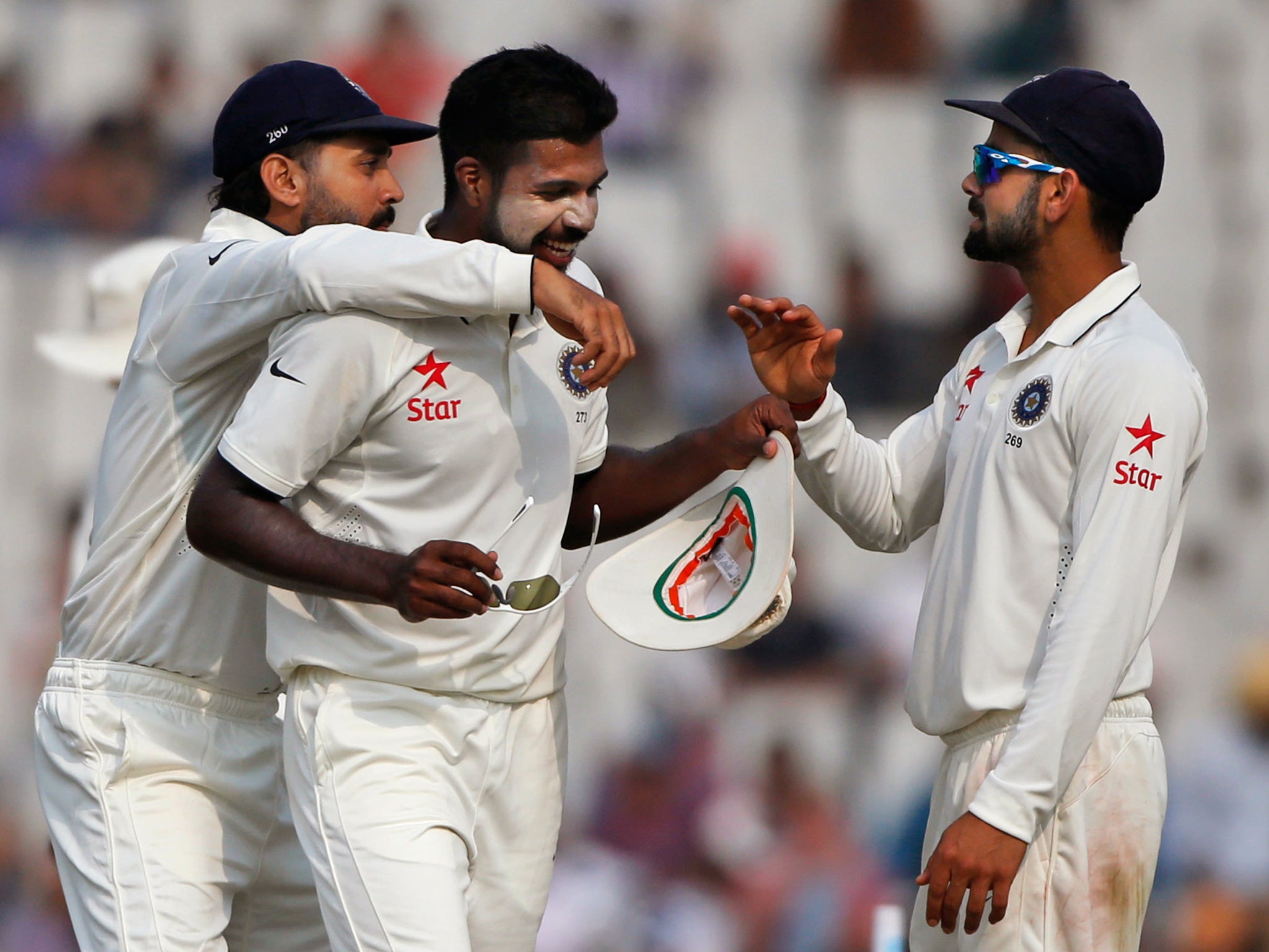 India's Varun Aaron, centre, captain Virat Kohli, right, and Murali Vijay celebrate the wicket of Simon Harmer during the third day of their test against South Africa