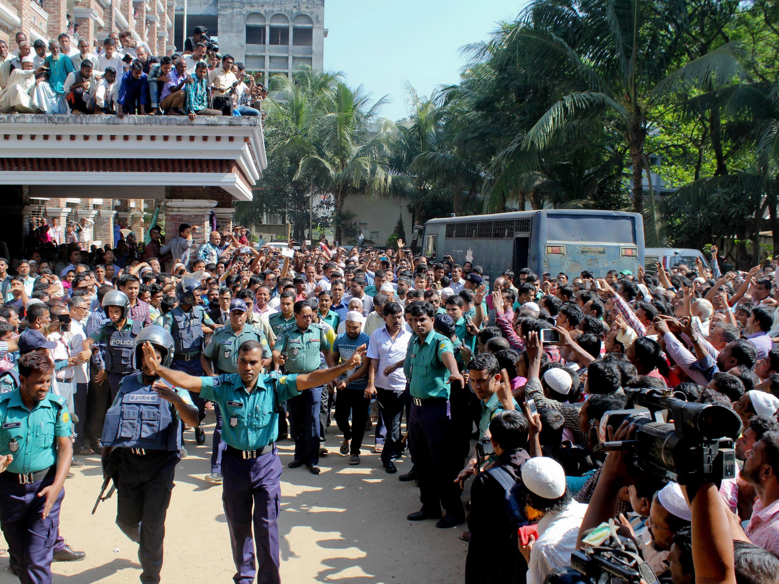 Bangladeshi people gather outside a court as police escort the accused youth in the killing of Bangladeshi boy Samiul Islam Rajon