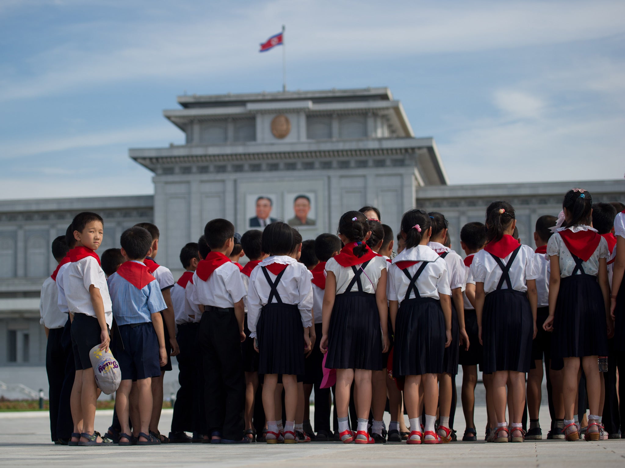 North Korean school children stand in front of the portraits of late North Korean leaders Kim Il-Sung (L) and Kim Jong-Il (R) at Kumsusan Palace