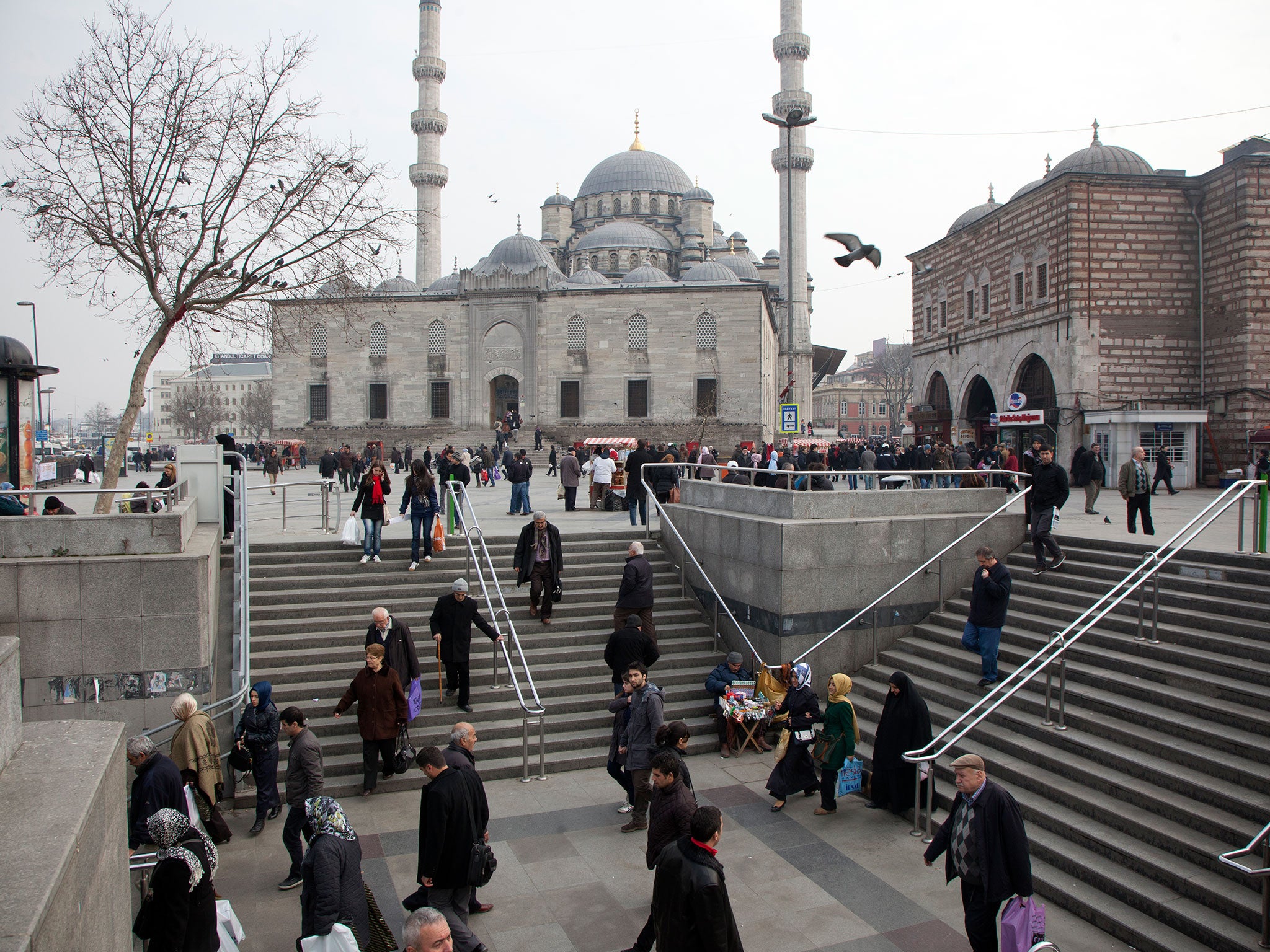 Commuters make their way into Istanbul's underground, with the New Mosque in the background
