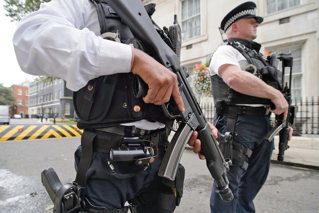Armed police officers hold guns as they stand in Downing Street