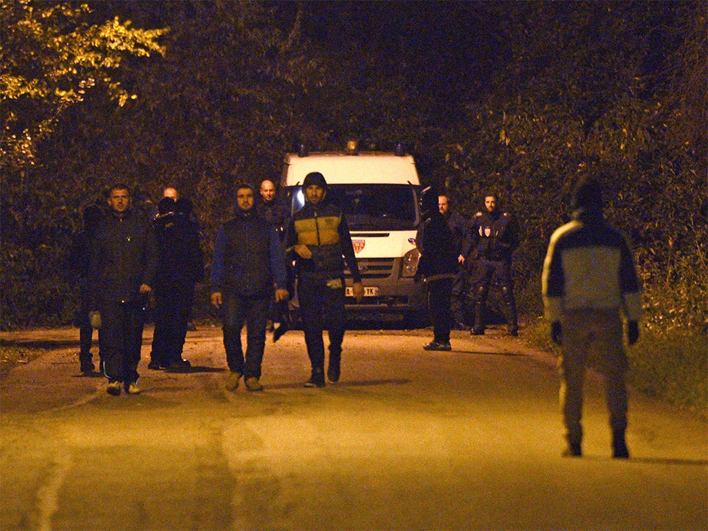 Migrants walk past French CRS police forces in Calais