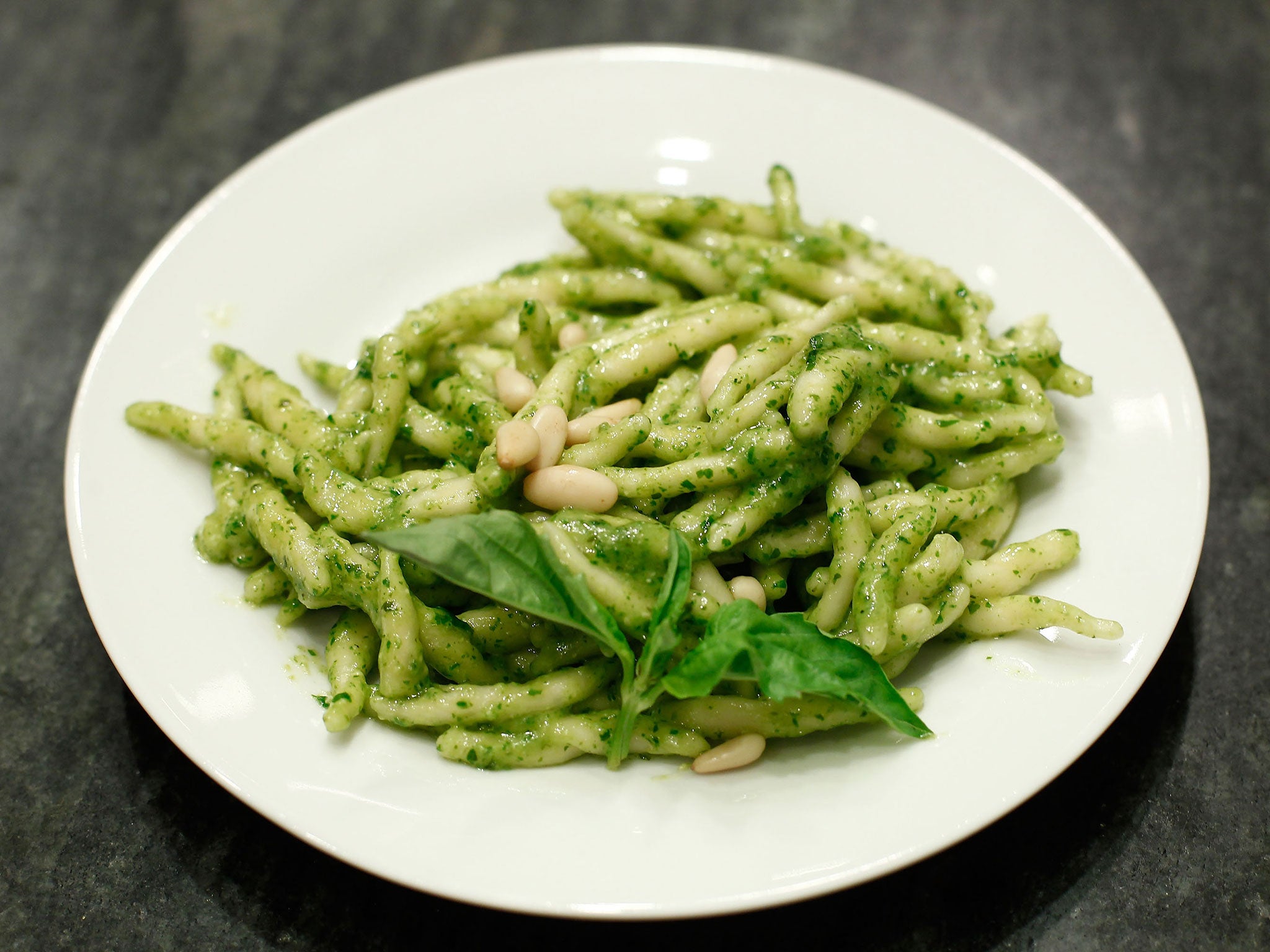 A dish of pasto and pesto with pinenuts