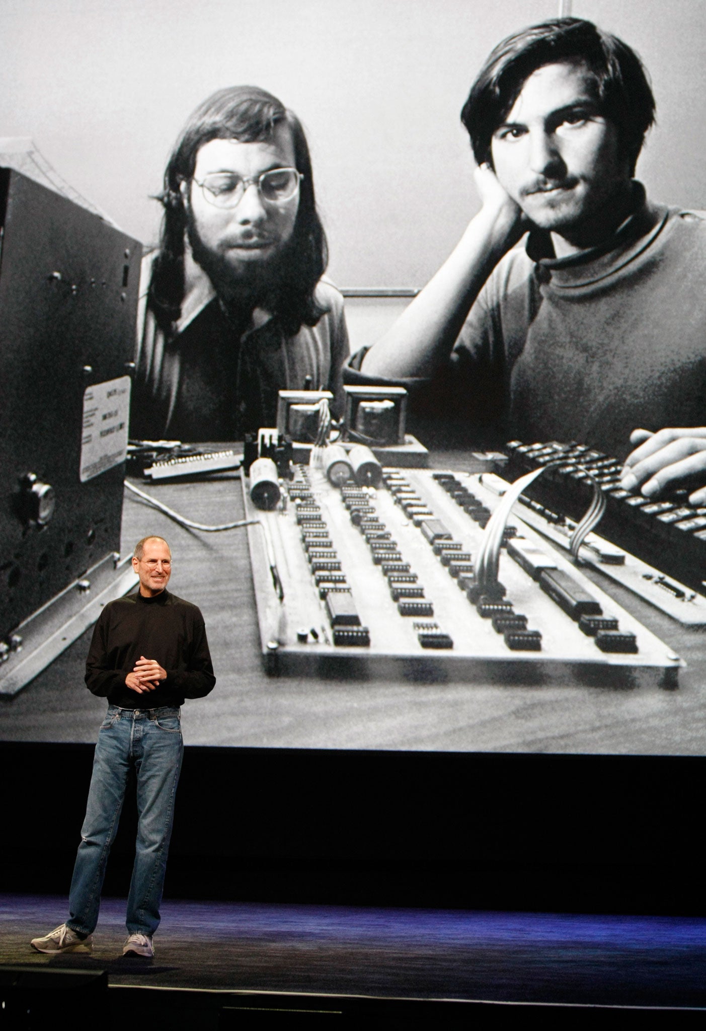 Jobs retiring in 2011 in front of a photograph of himself and Steve Wozniak