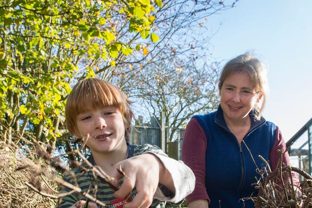 Rebecca Mitchell supervises her son Jamie as he cuts some branches with secateurs