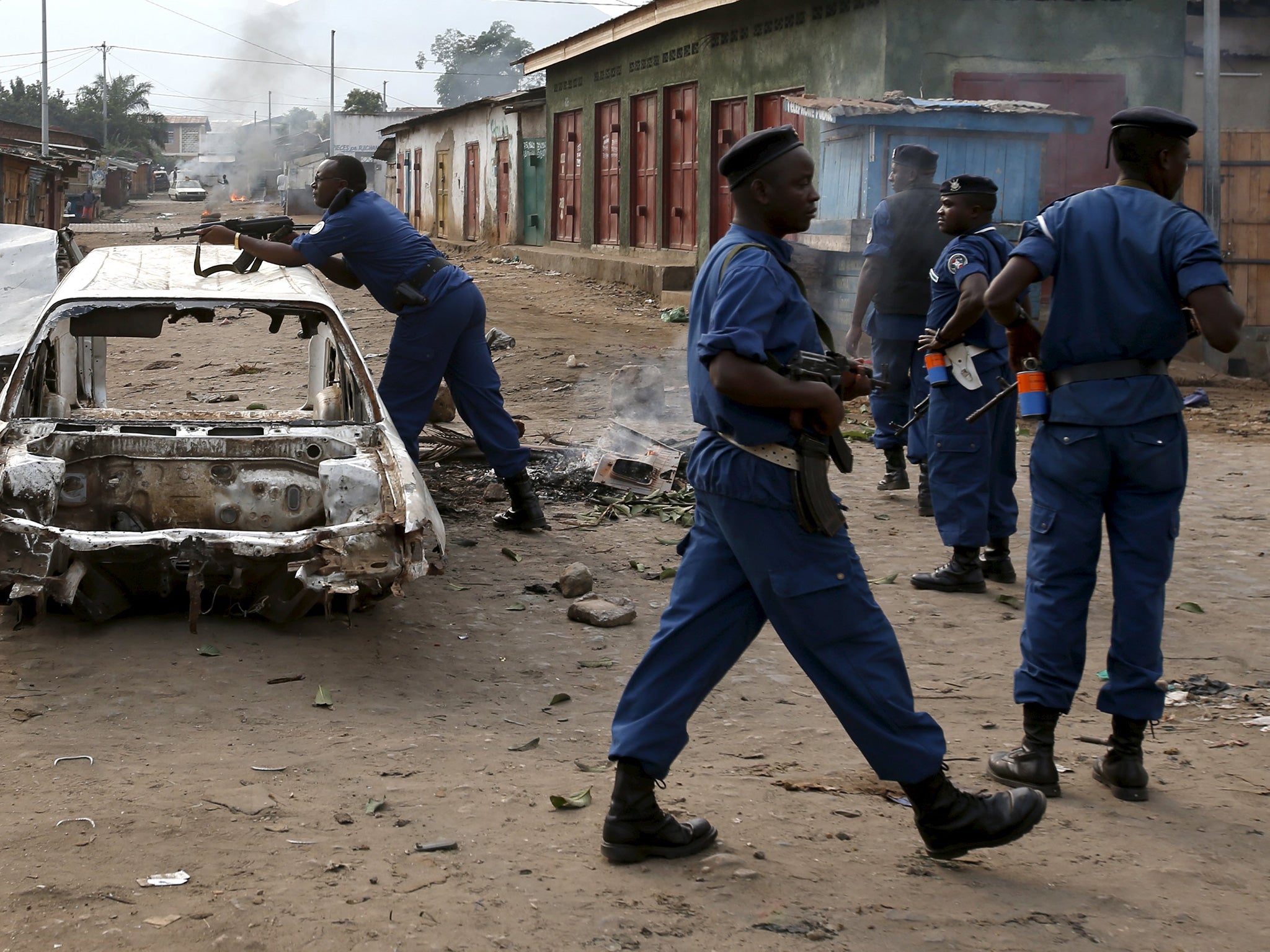 Police point a rifle at protesters who erected a barricade in protest against Pierre Nkurunziza
