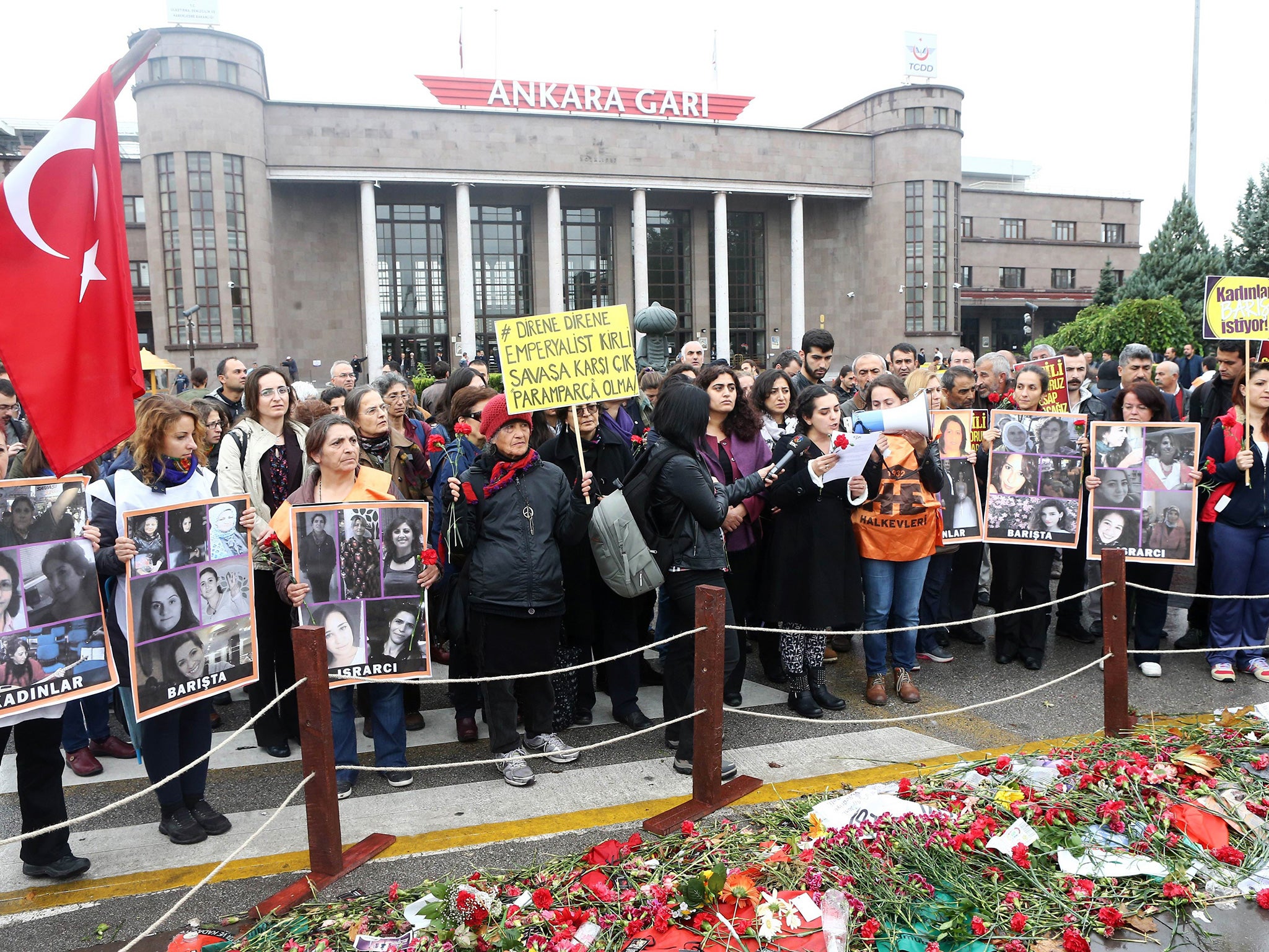 Mourners in Ankara hold images of victims and banners as they gather at the site of twin explosions that killed 102 people