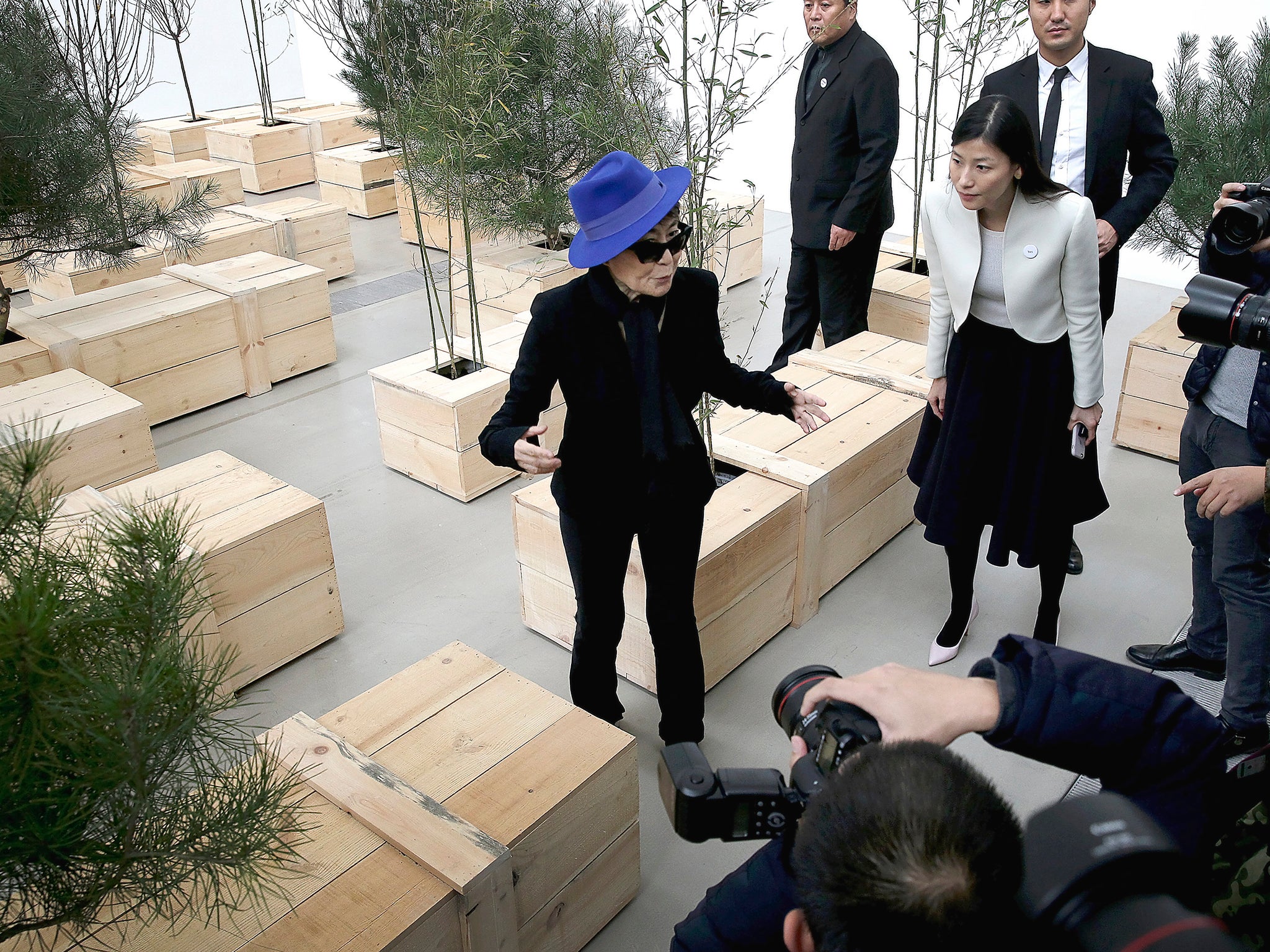 Artist Yoko Ono poses for photographers with one of her art installation "Ex It" wooden coffins with pine, bamboo and plum trees on display at her exhibition held at the 798 art district in Beijing, China