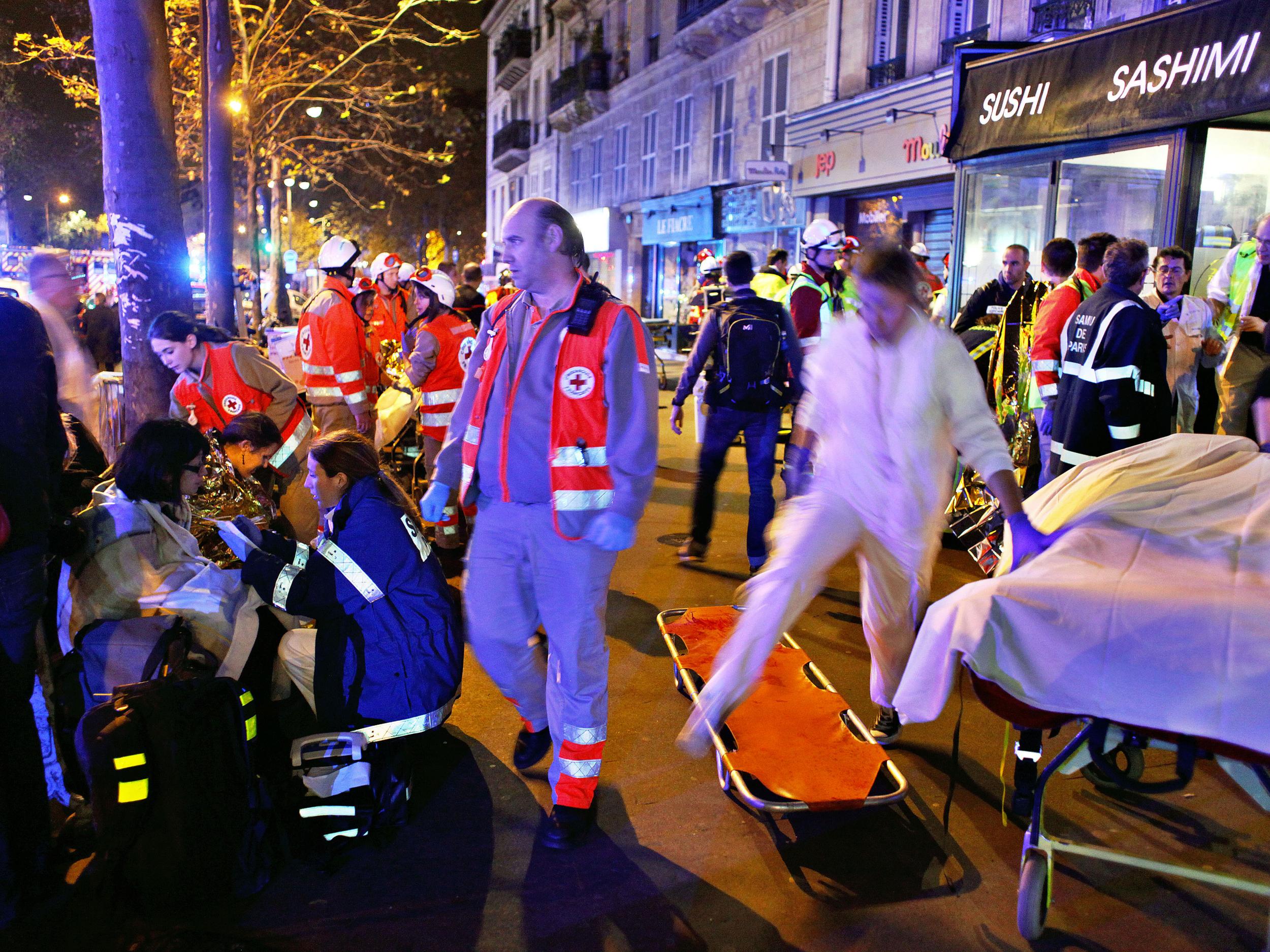 People rest on a bench after being evacuated from the Bataclan theater after a shooting in Paris AP