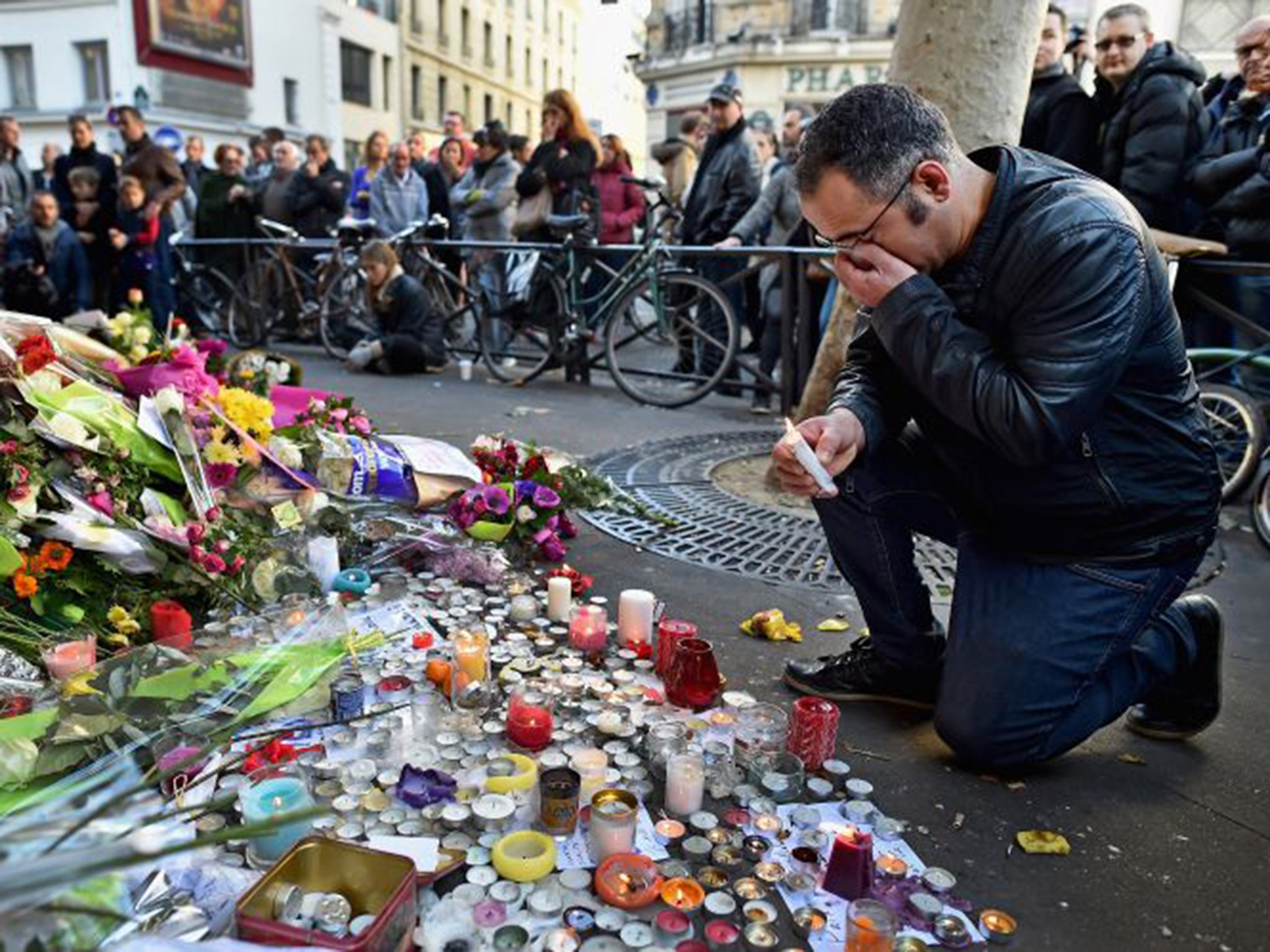 Members of the public gather to lay flowers and light candles at La Belle Equipe restaraunt on Rue de Charonne following Friday's terrorist attack