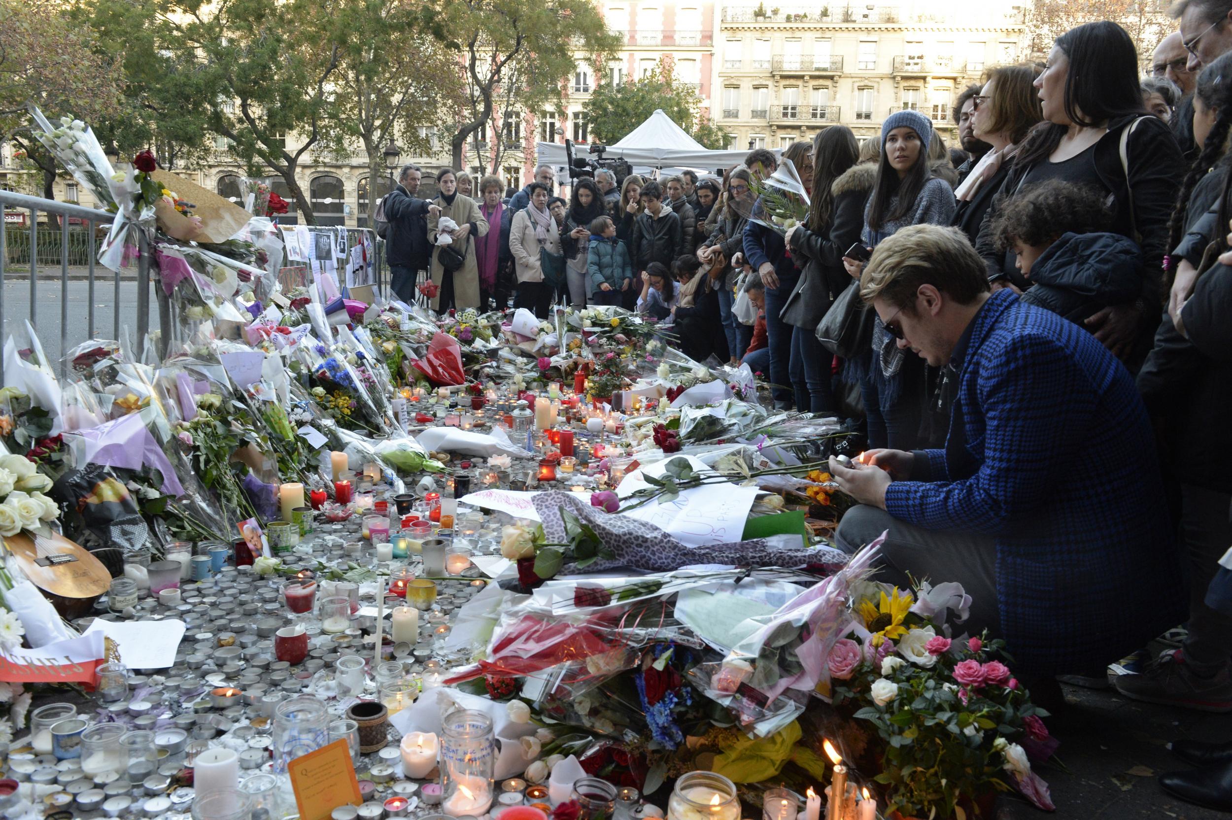 People mourn outside a makeshift memorial at the Bataclan concert hall in Paris