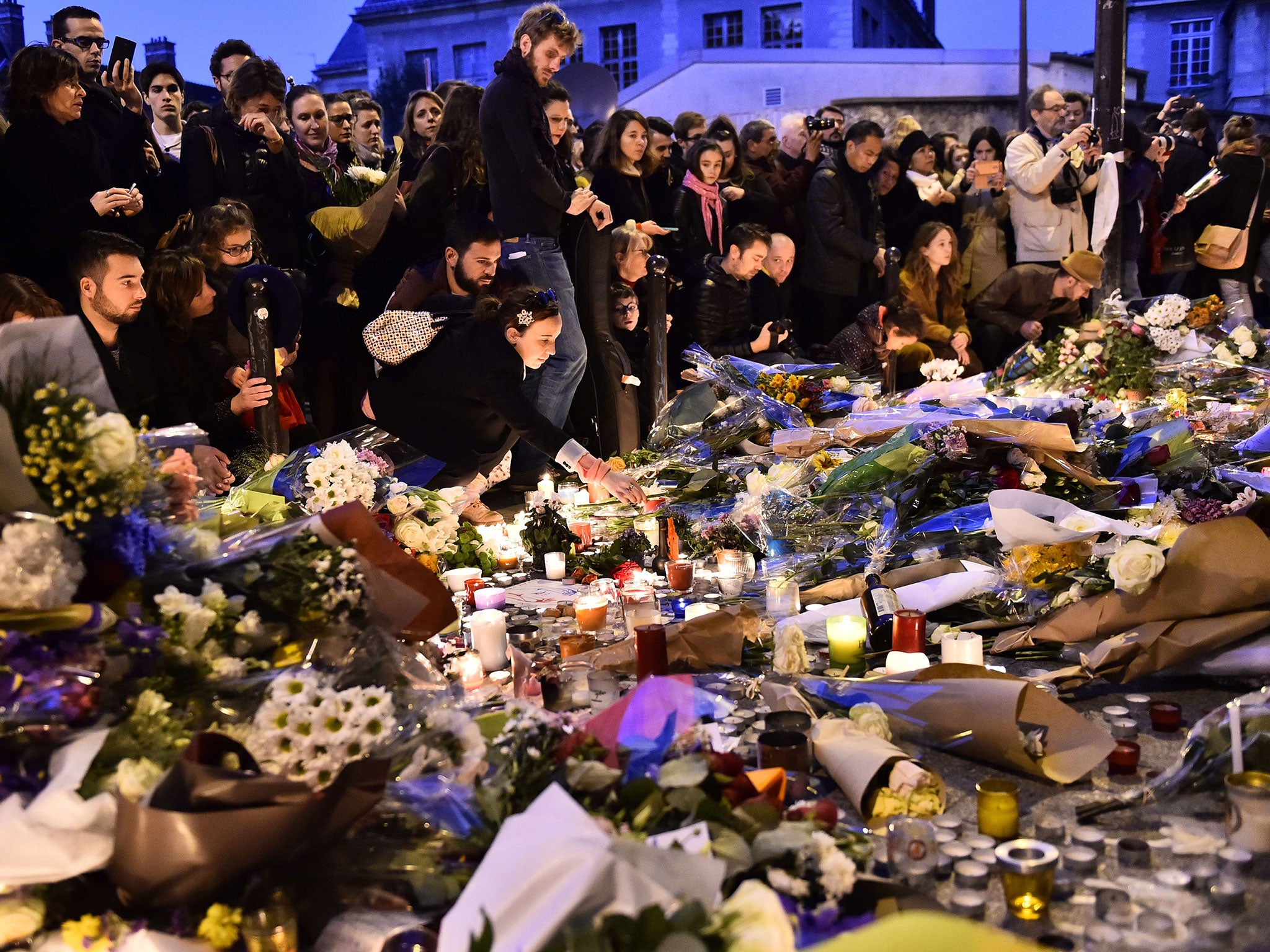 People lay flowers at a makeshift memorial in front of 'Le carillon' restaurant one of the site of the attacks in Paris