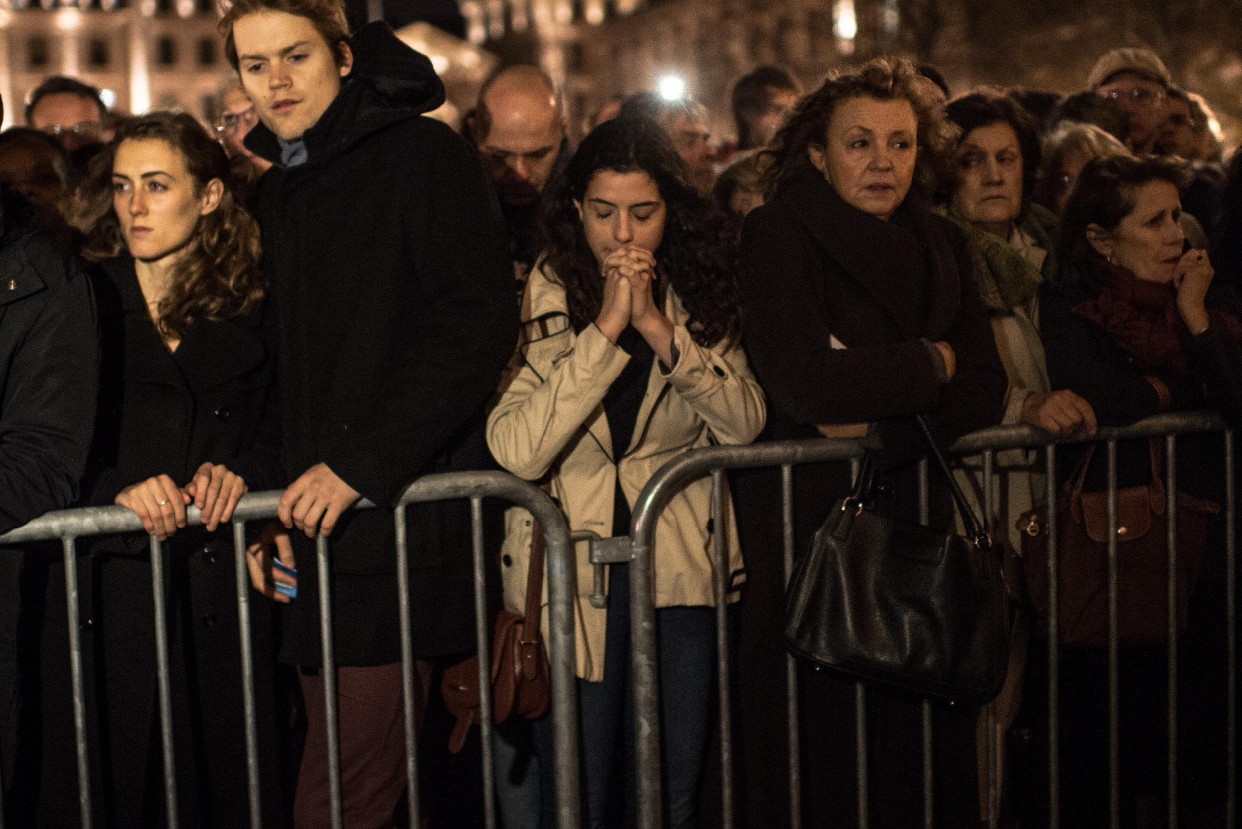 People gather and pray outside of Notre Dame Cathedral ahead of a ceremony to the victims of the Friday's terrorist attack.