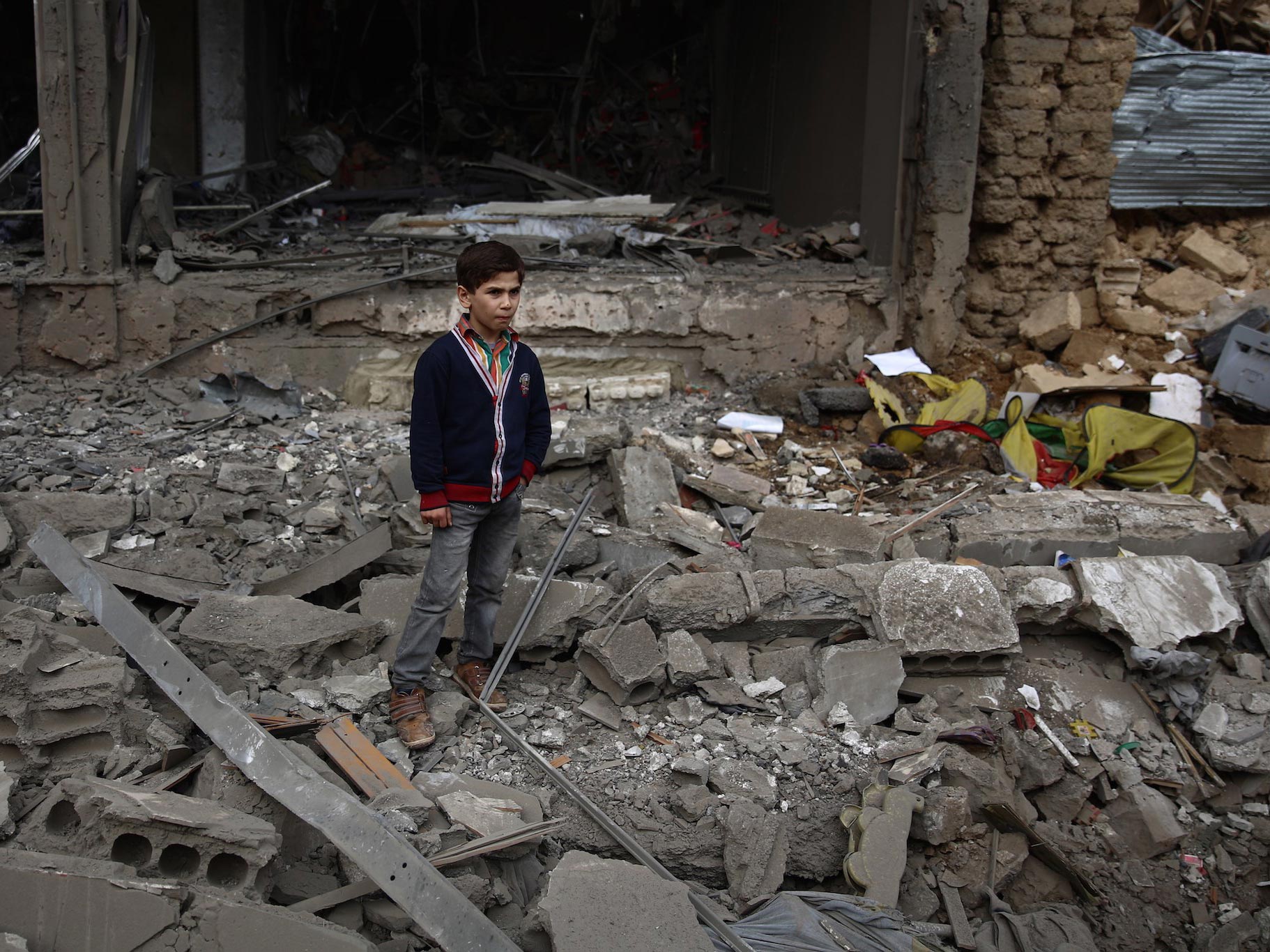 A young boy stands amid debris following a reported air strike in Syria
