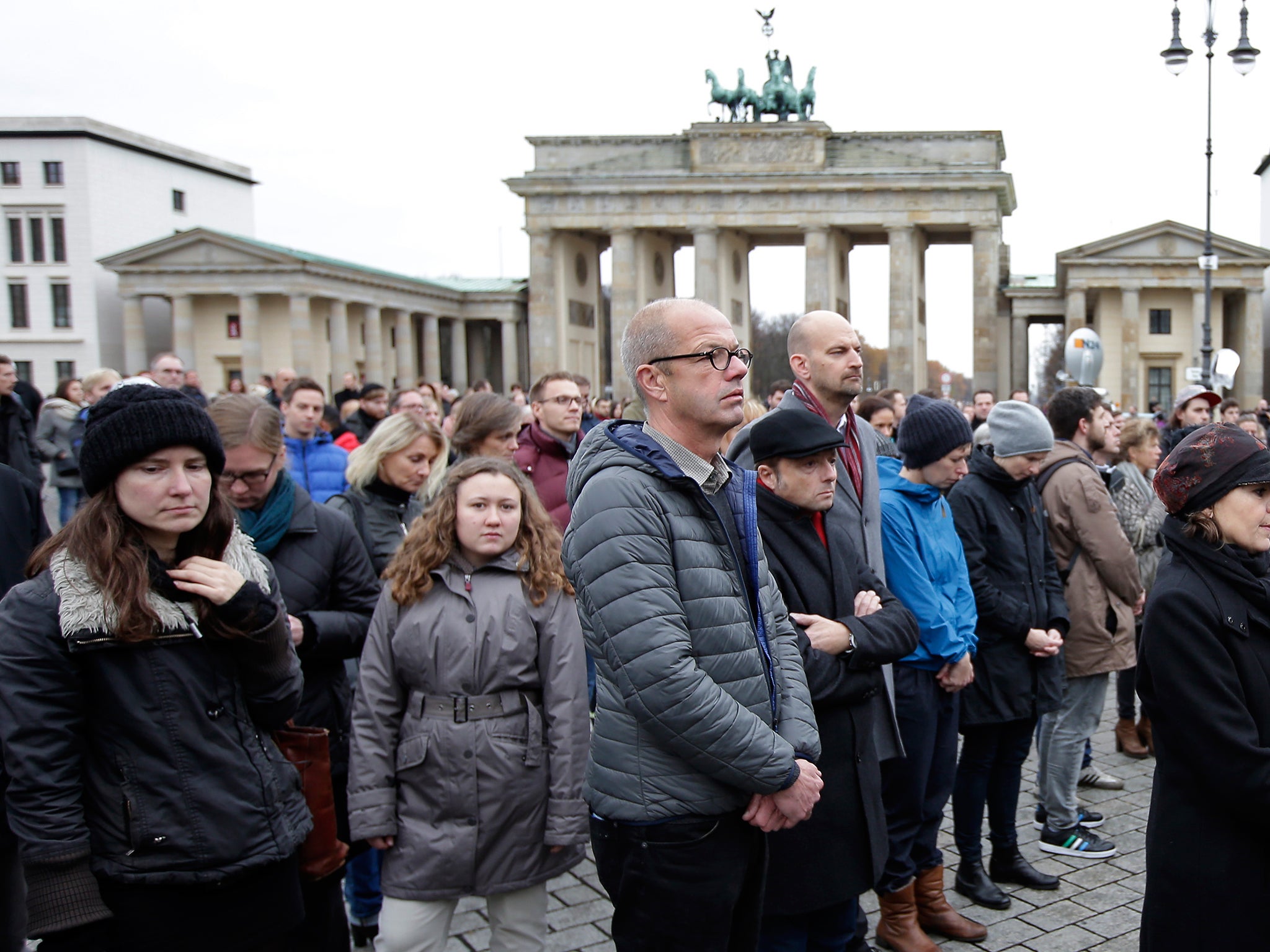 People stand still during a minute of silence at the Brandenburg Gate in Berlin, to honor the victims of the terrorist attacks in France