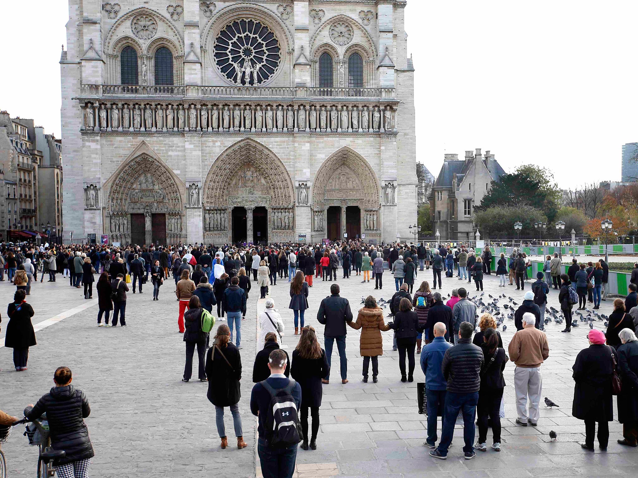 People observe a minute of silence in front of the Notre Dame Cathedral in Paris