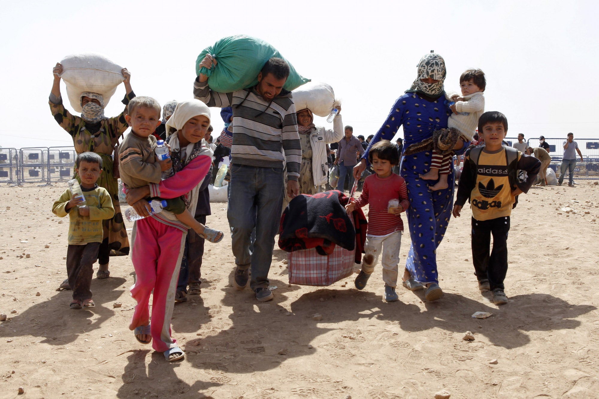 People walk with their belongings across the Syrian border town of Kobani.